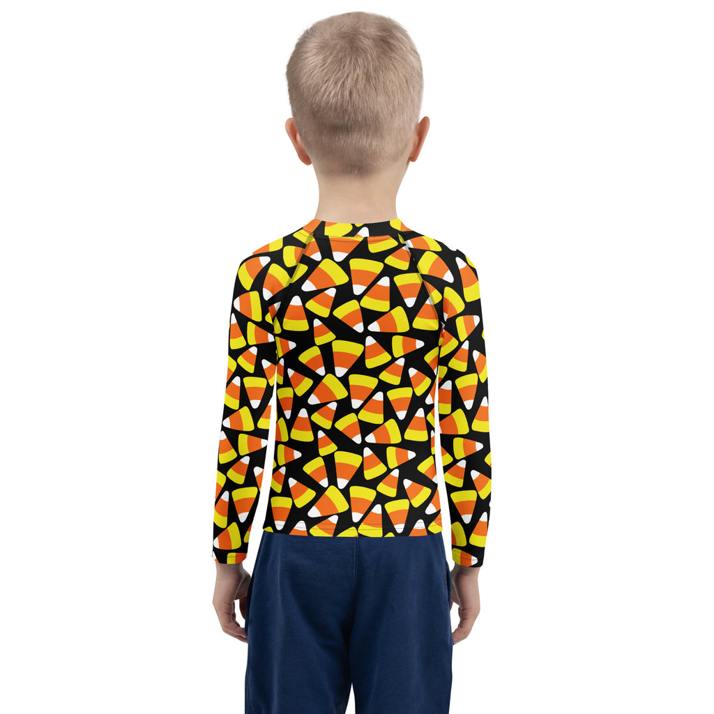 A child wearing a black kids candy corn halloween long sleeve rash guard swim shirt with upf 50 plus protection