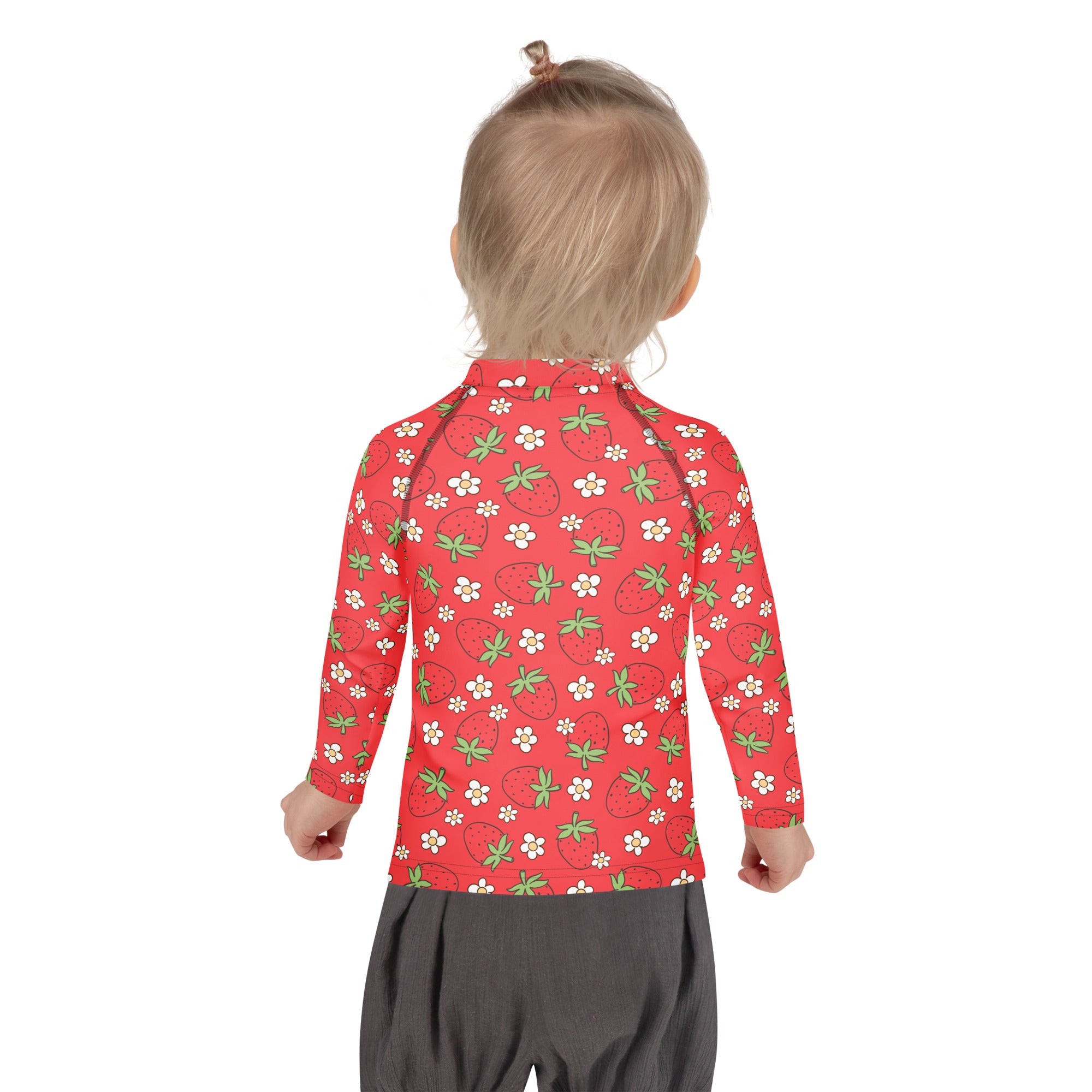 A child wearing a red strawberry long sleeve rash guard swim shirt with UPF 50+ and a green-stemmed strawberry pattern