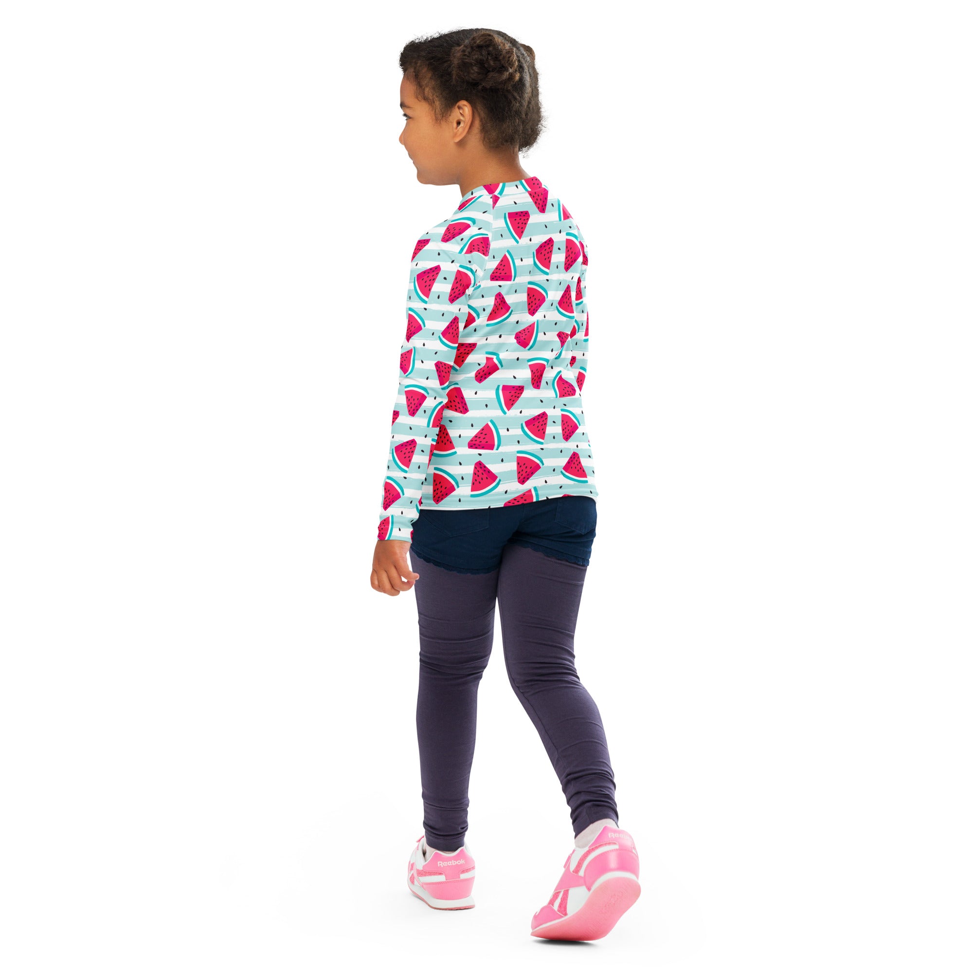 A child wearing a kids striped watermelon long sleeve rash guard swim shirt with upf 50 plus and dark leggings