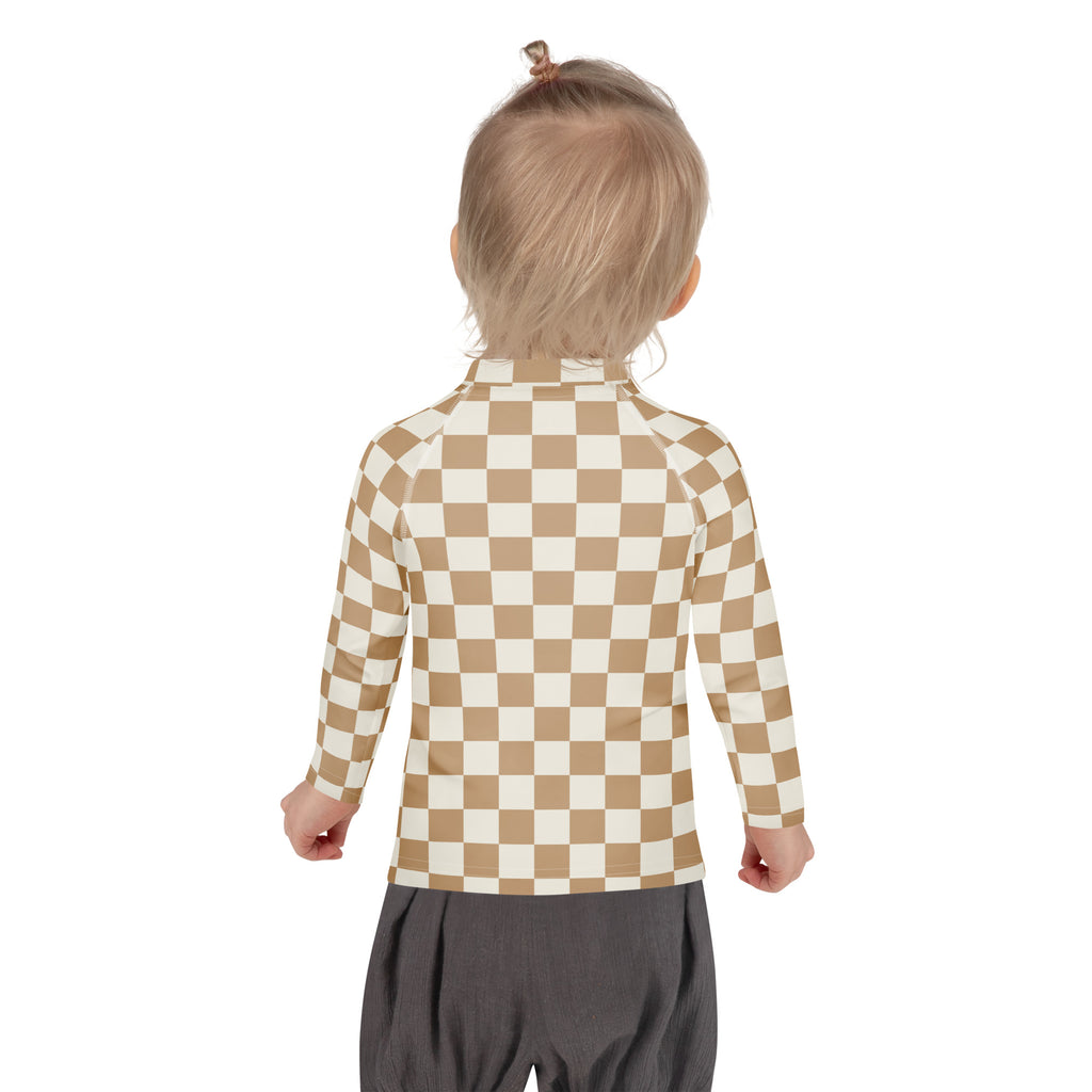 A child wearing a tan and cream checkered kids sand checkerboard long sleeve rash guard with UPF 50+