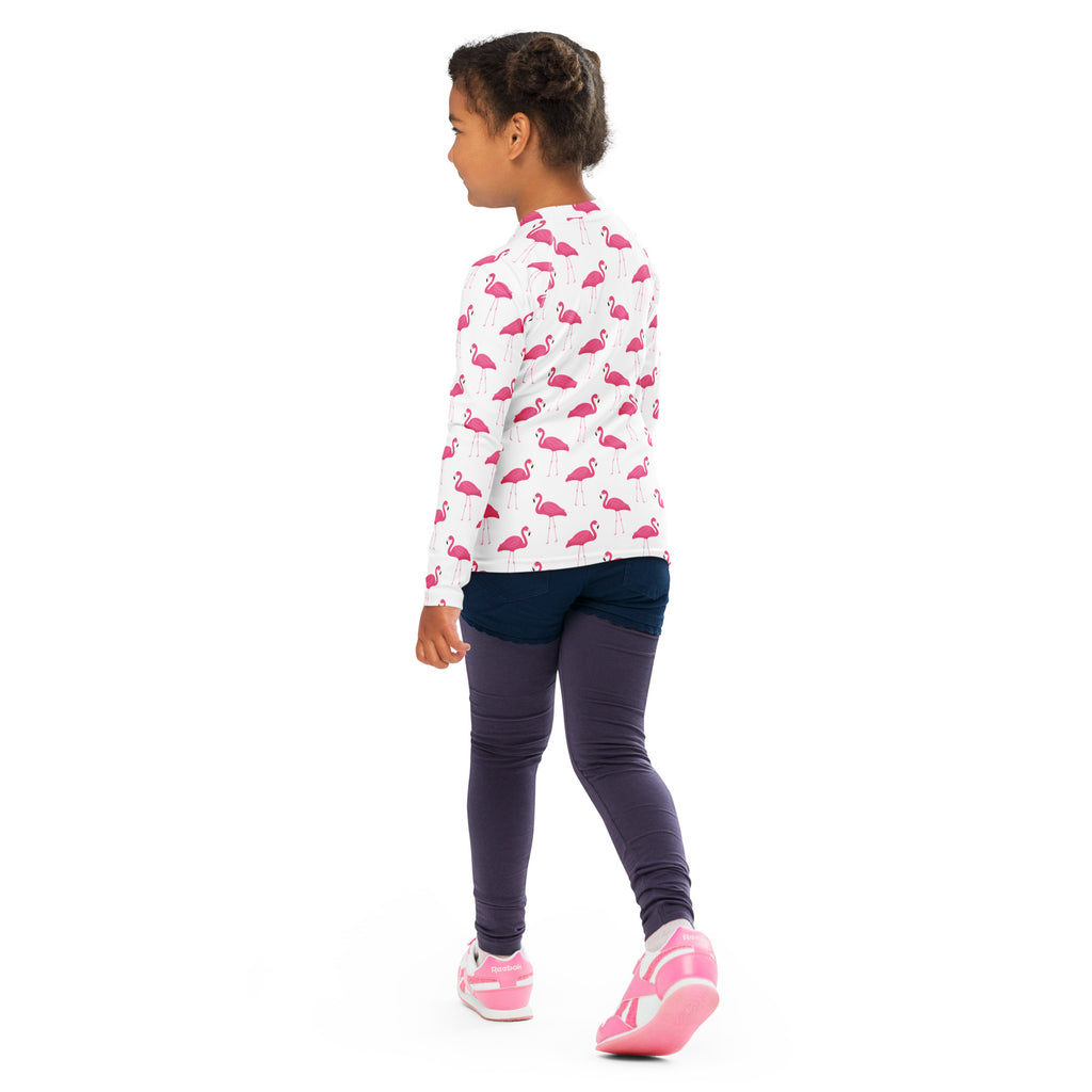 A kids pink flamingo long sleeve white rash guard swim shirt with a repeating pattern and upf 50 plus protection