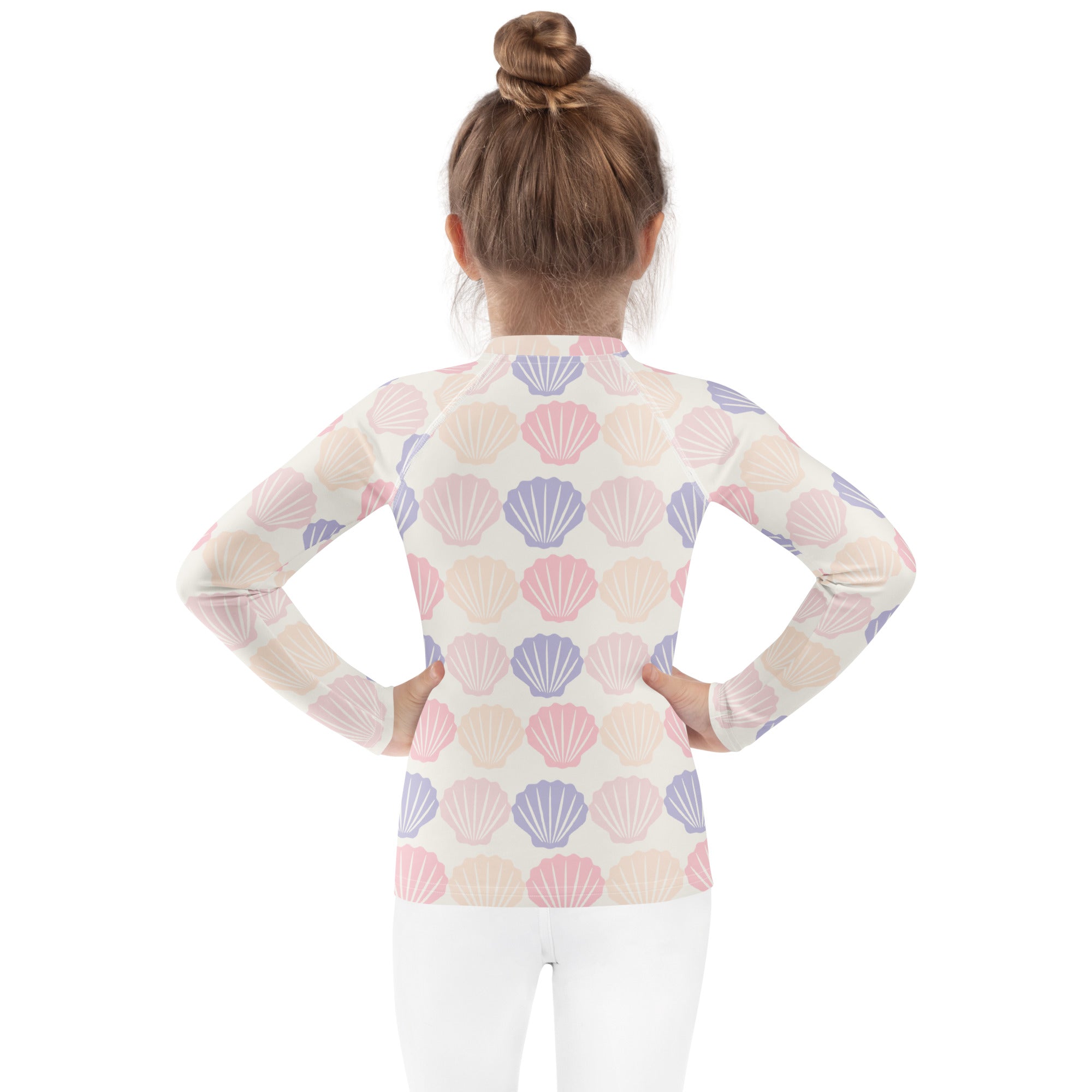 A girl wearing a kids seashell print long sleeve rash guard swim shirt with UPF 50 plus in pastel colors