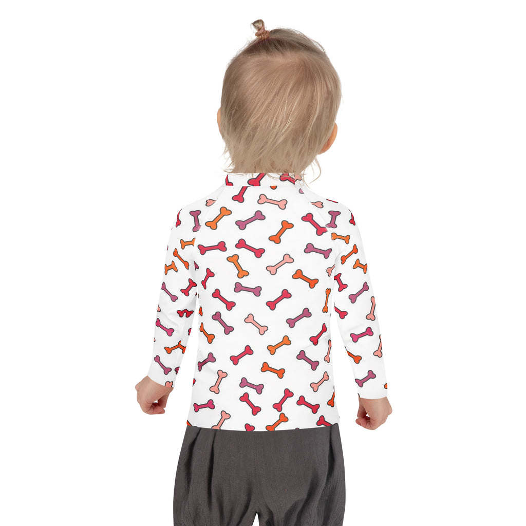 A child wearing a white kids dog bone long sleeve rash guard swim shirt with multicolored bone pattern and UPF 50+ protection