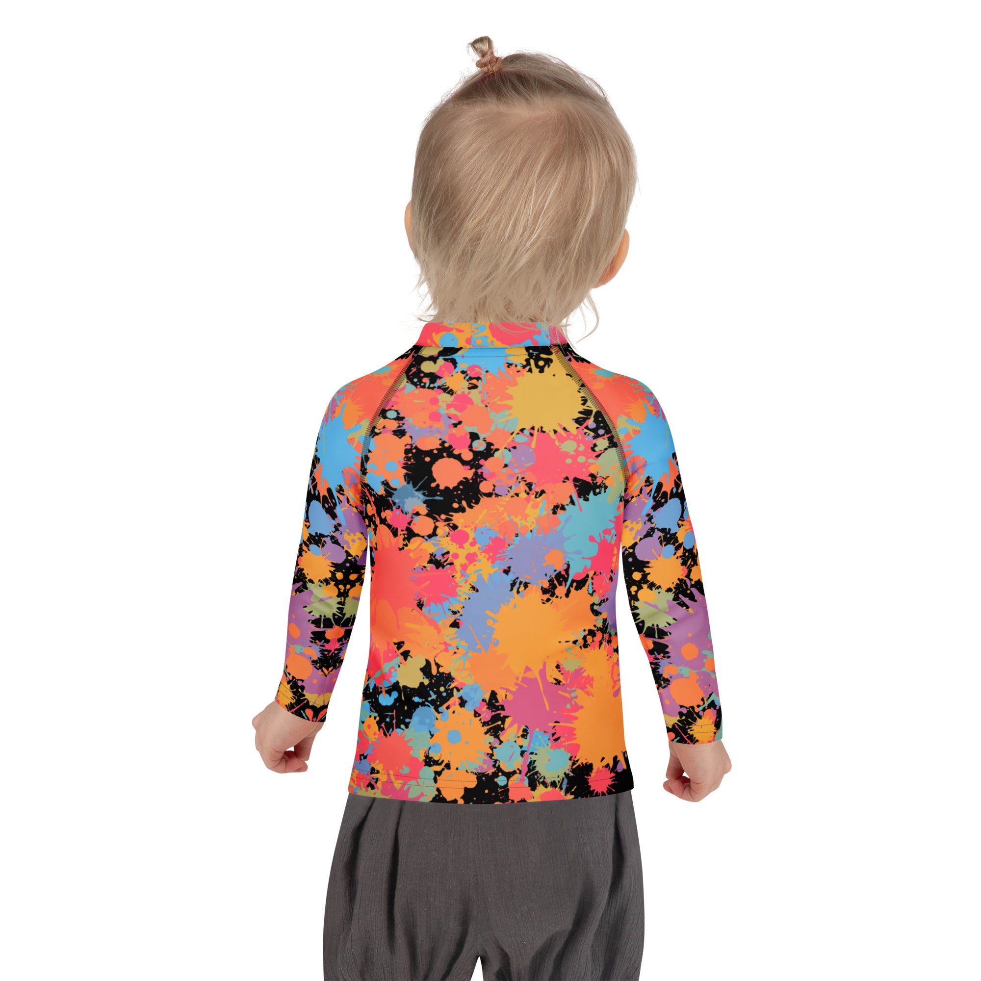 A child wearing a kids paint splatter long sleeve rash guard swim shirt with upf 50+ in vibrant colors on black fabric