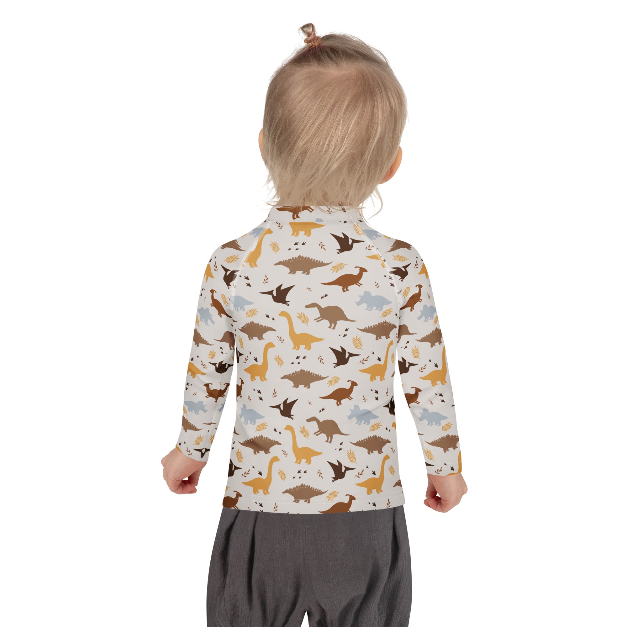A child wearing a kids dinosaur long sleeve rash guard swim shirt with UPF 50+ in earthy tones on off-white background