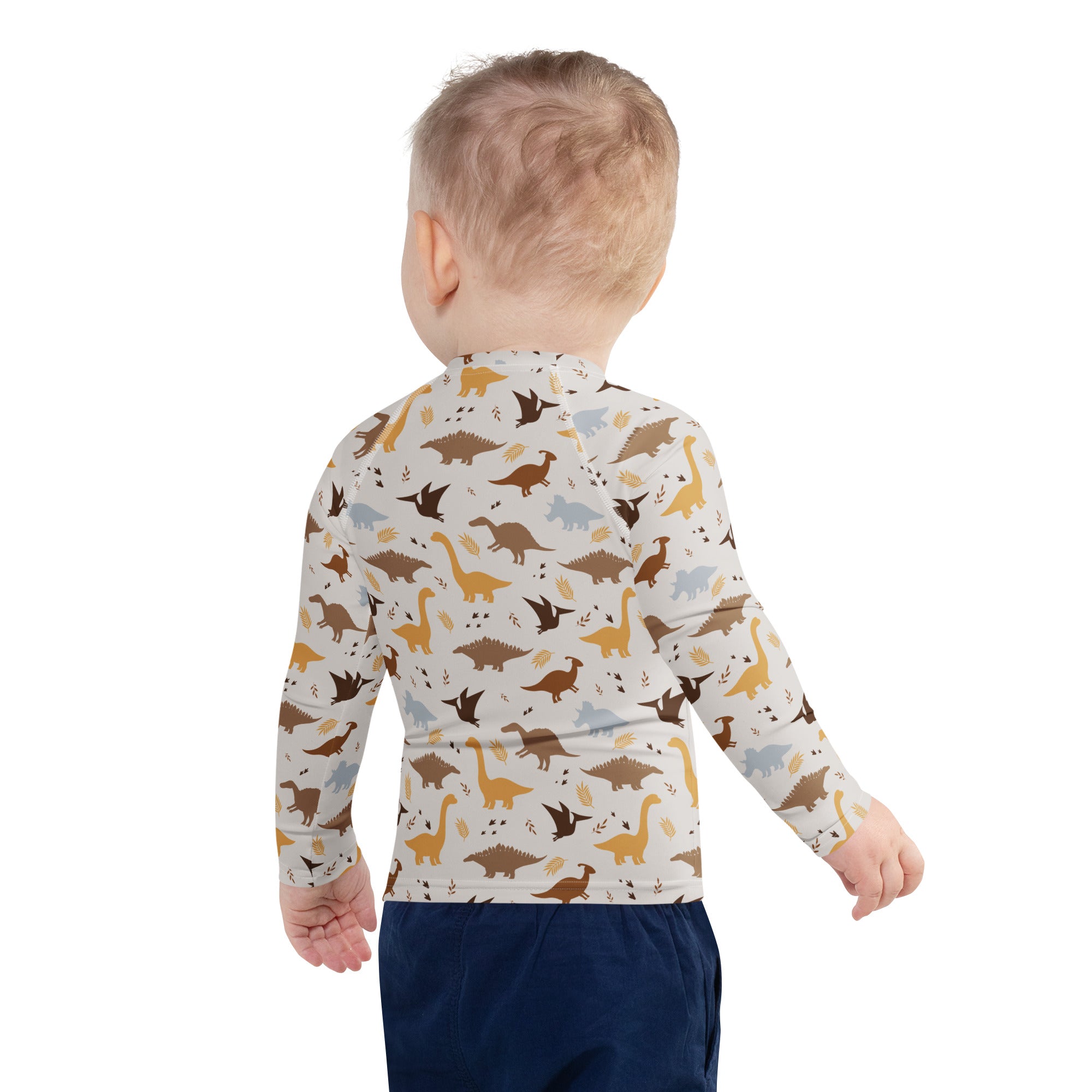 A child wearing a cream kids dinosaur long sleeve rash guard swim shirt with UPF 50 and playful dinosaur patterns