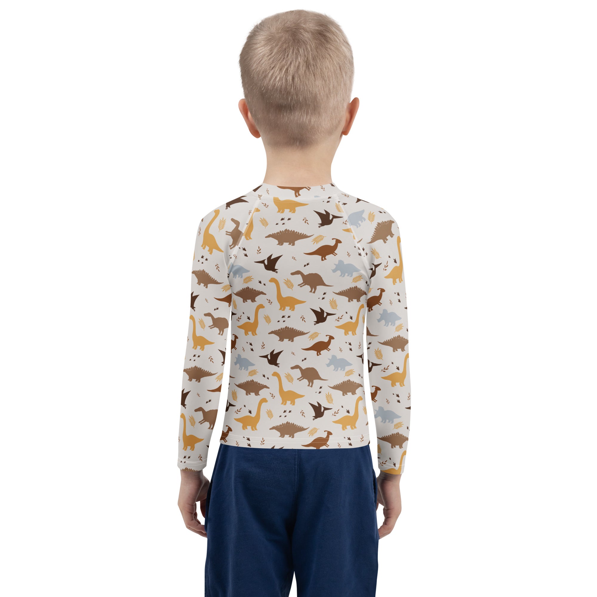 A child wearing a kids dinosaur long sleeve rash guard swim shirt with upf 50 plus in earthy tones on off white background