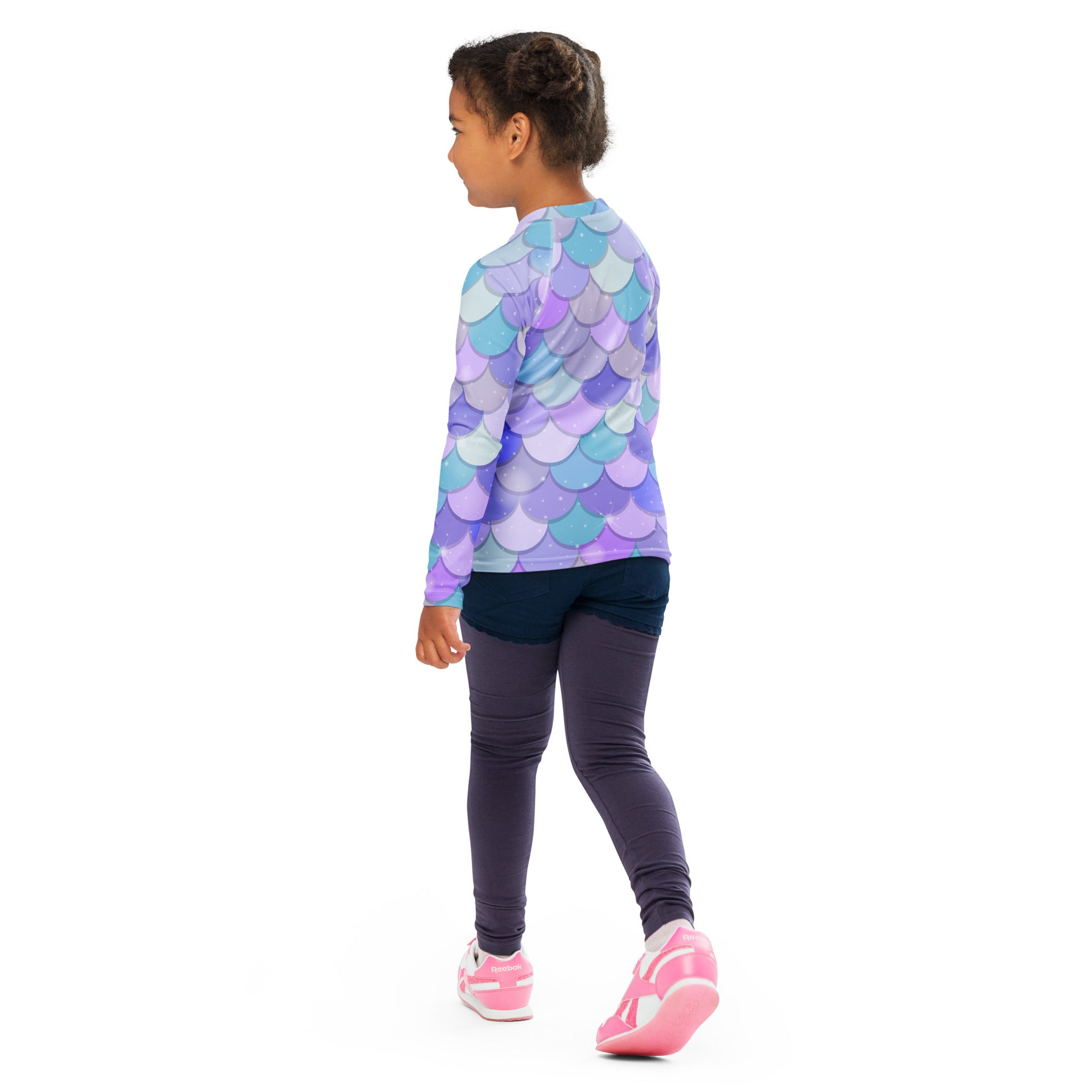 A girl wearing a purple and blue shimmering mermaid scales long sleeve rash guard swim shirt with UPF 50+