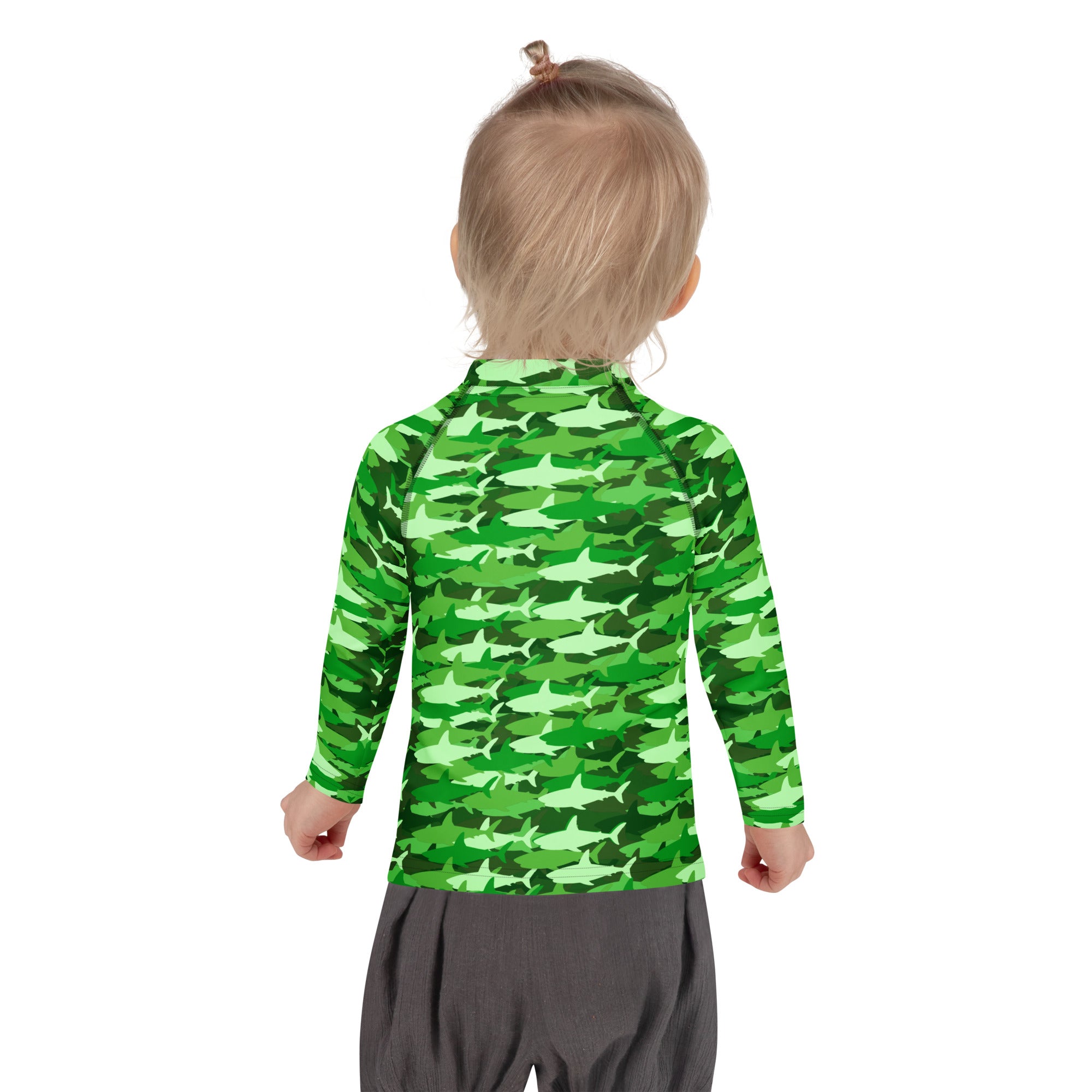 A child wearing a kids green shark long sleeve rash guard swim shirt with UPF 50 plus and all-over shark pattern