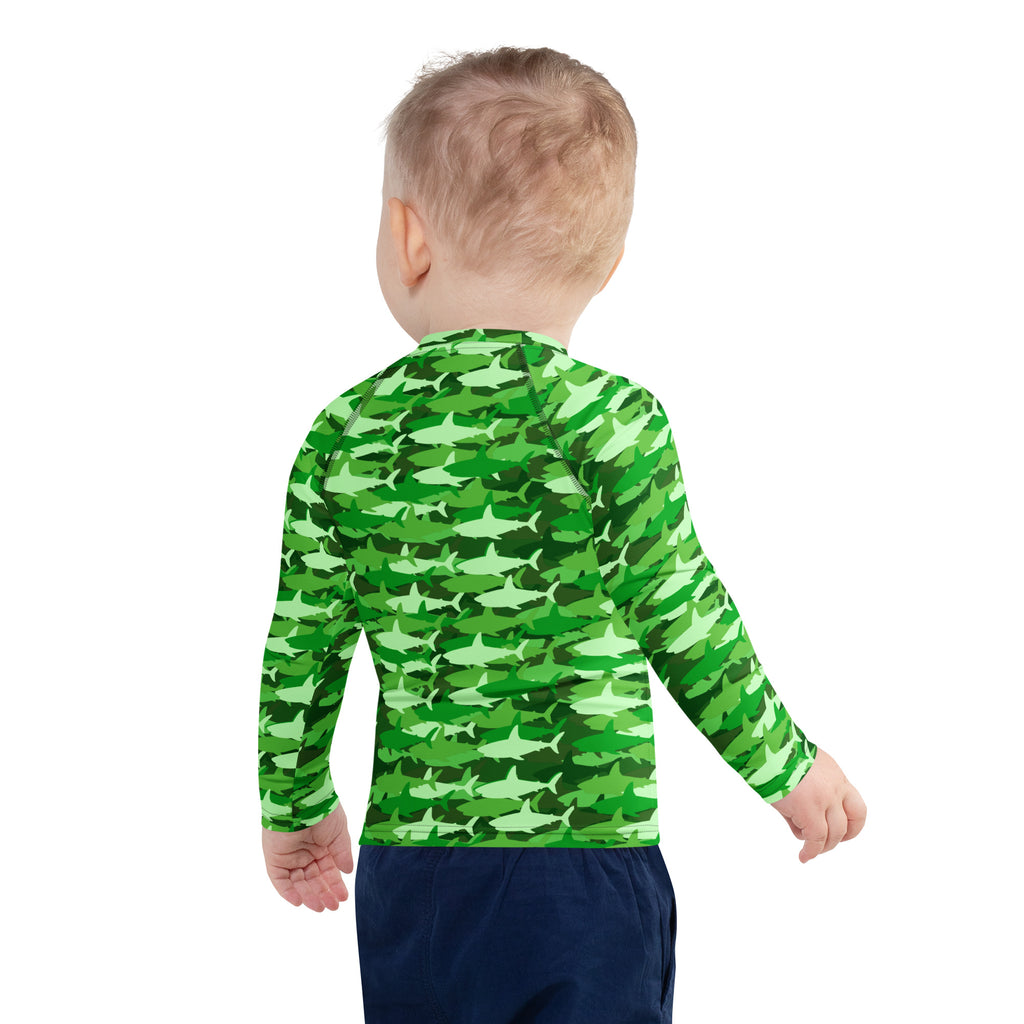 A child wearing a kids green shark long sleeve rash guard swim shirt with UPF 50 plus and shark camouflage pattern