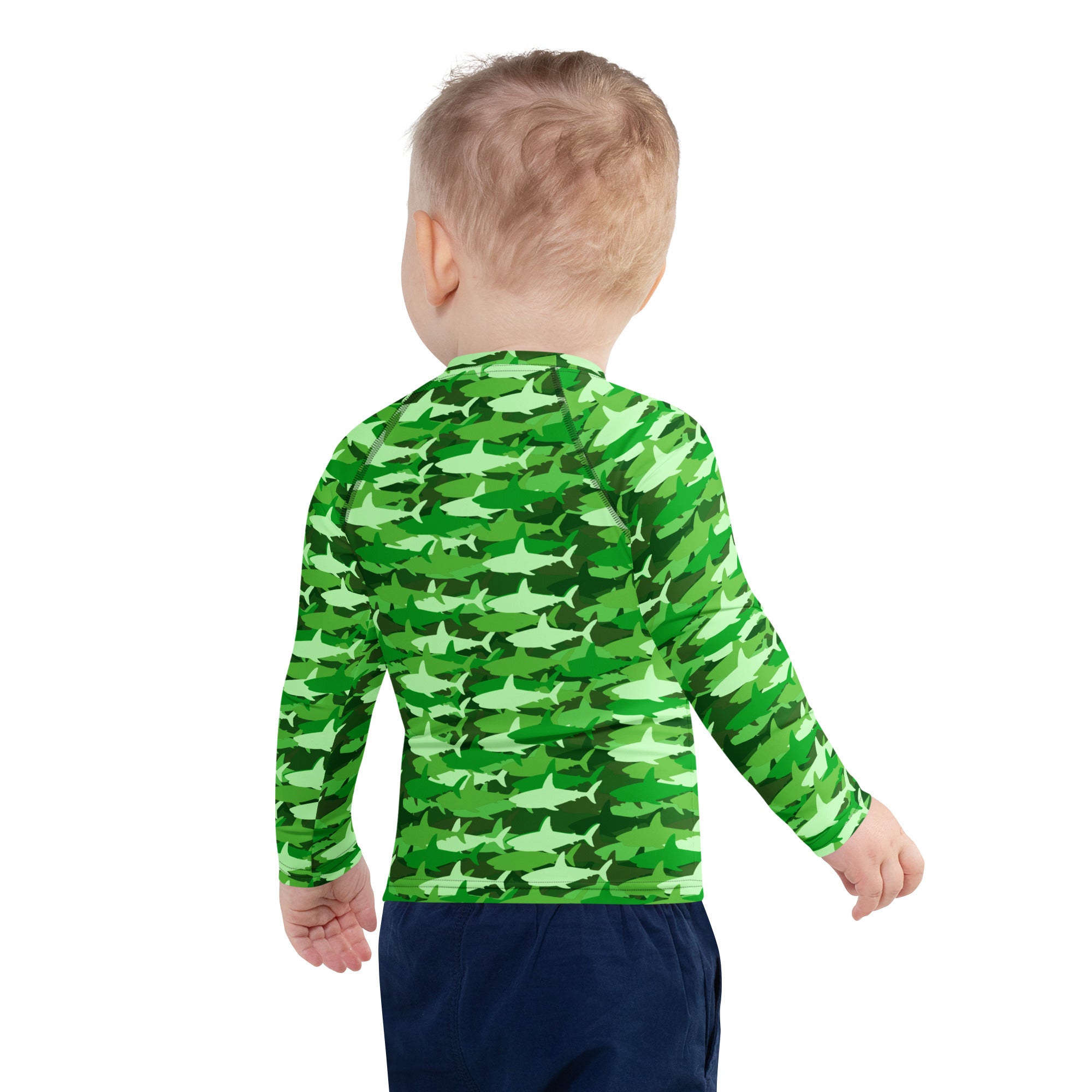 A child wearing a kids green shark long sleeve rash guard swim shirt with UPF 50 plus and shark camouflage pattern