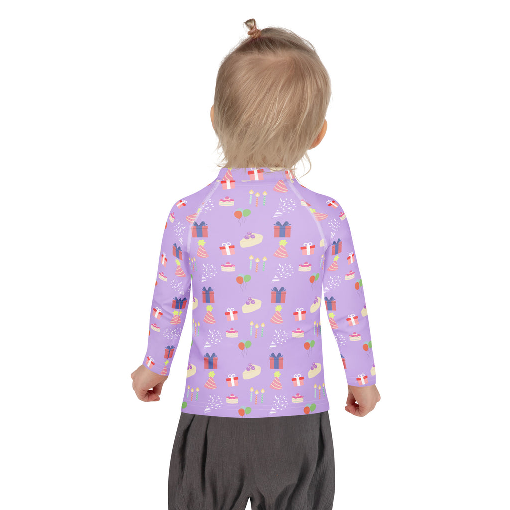 A child wearing a girls purple birthday pattern long sleeve rash guard swim shirt with UPF 50 plus protection