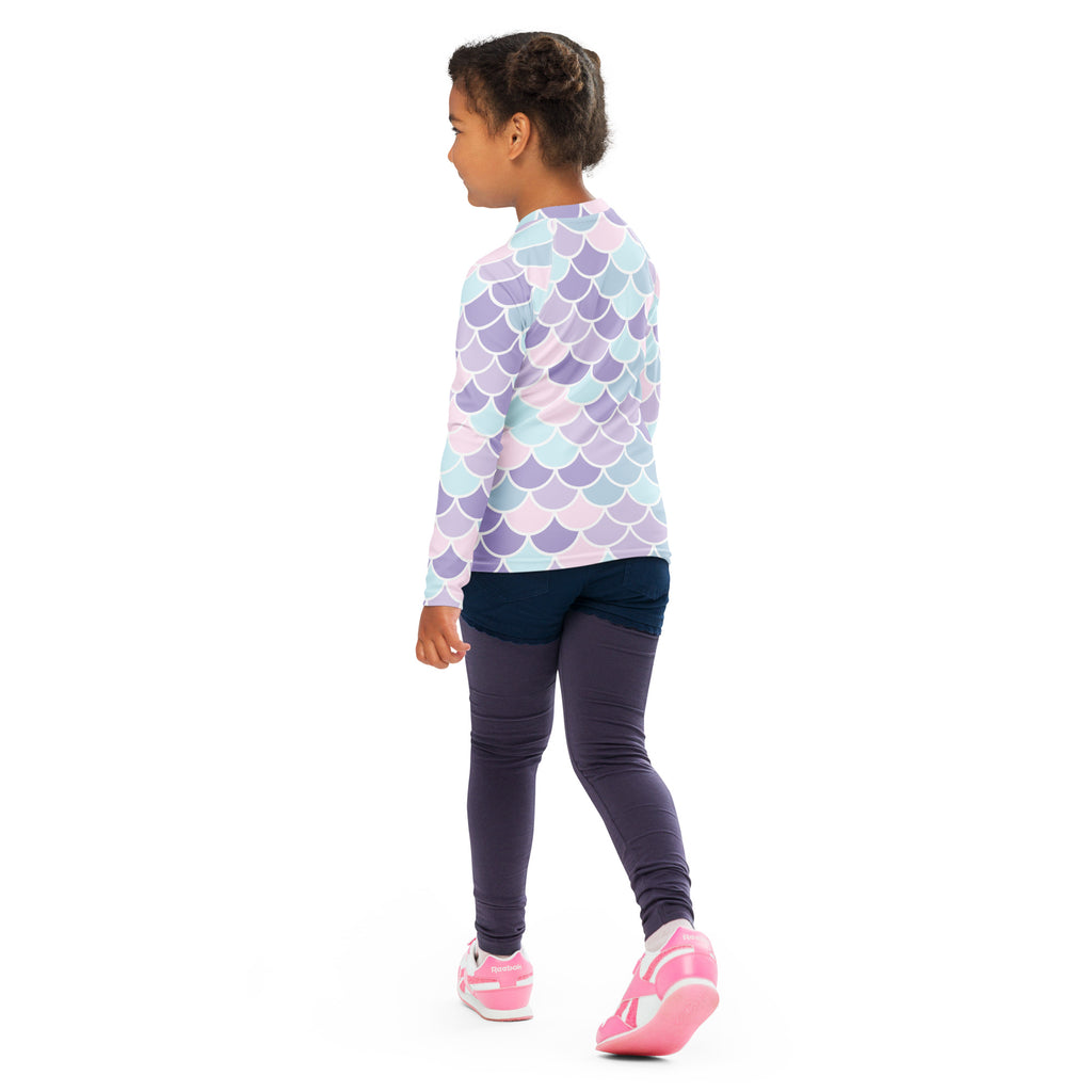 A child wearing a girls mermaid scale long sleeve rash guard swim shirt with pastel lavender blue scales and upf 50+ protection