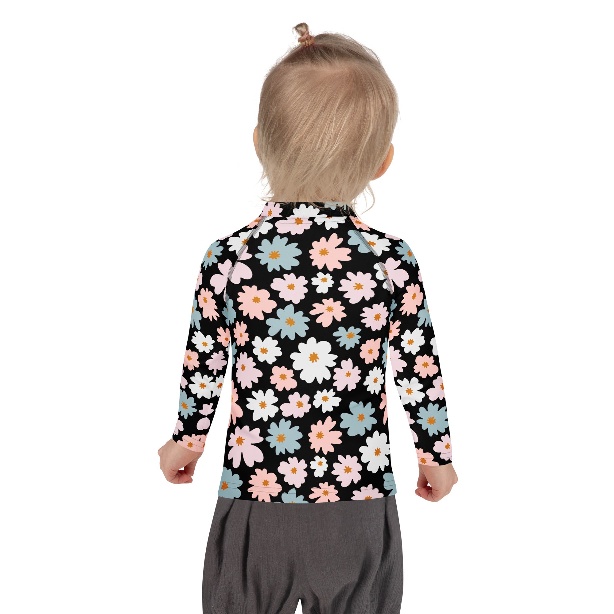 A child wearing a black girls flower scale long sleeve rash guard with pink white and blue daisy pattern and UPF 50+ protection