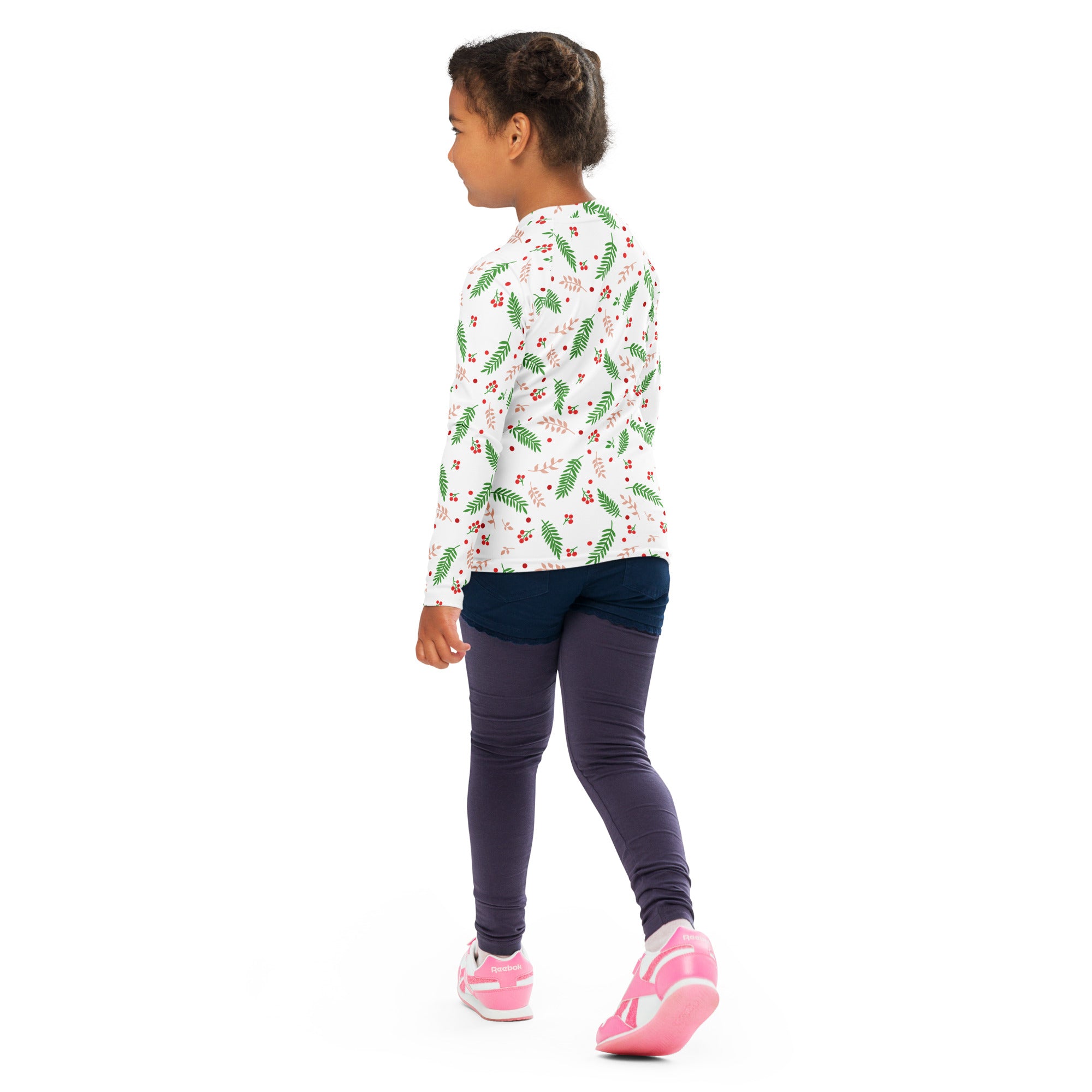 Kids holly and evergreen Christmas long sleeve rash guard swim shirt with green fern red berry pattern and UPF 50+ paired with pink sneakers