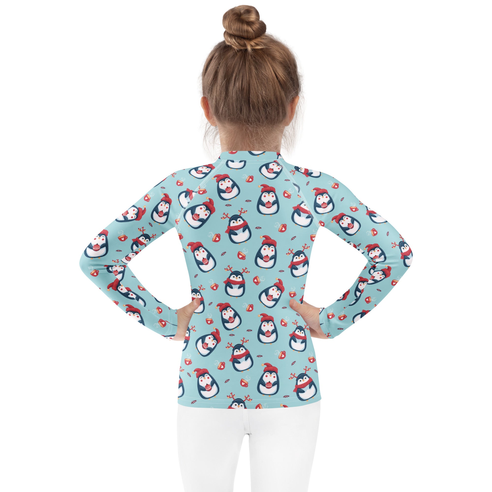 A light blue kids long sleeve rash guard swim shirt with cartoon penguins wearing red hats and scarves and upf 50+ protection