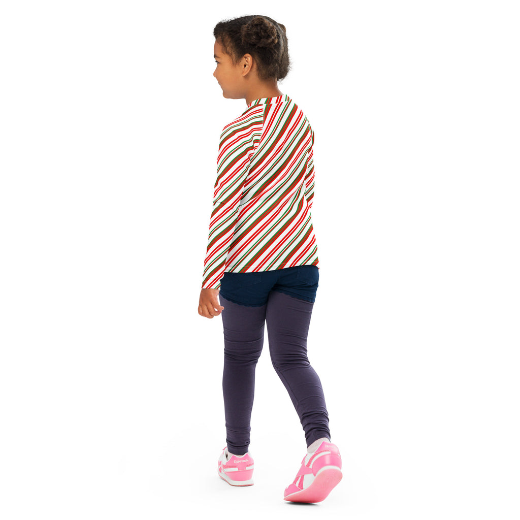 A child wearing a kids candy cane stripe Christmas long sleeve rash guard swim shirt with UPF 50 plus in red white and brown