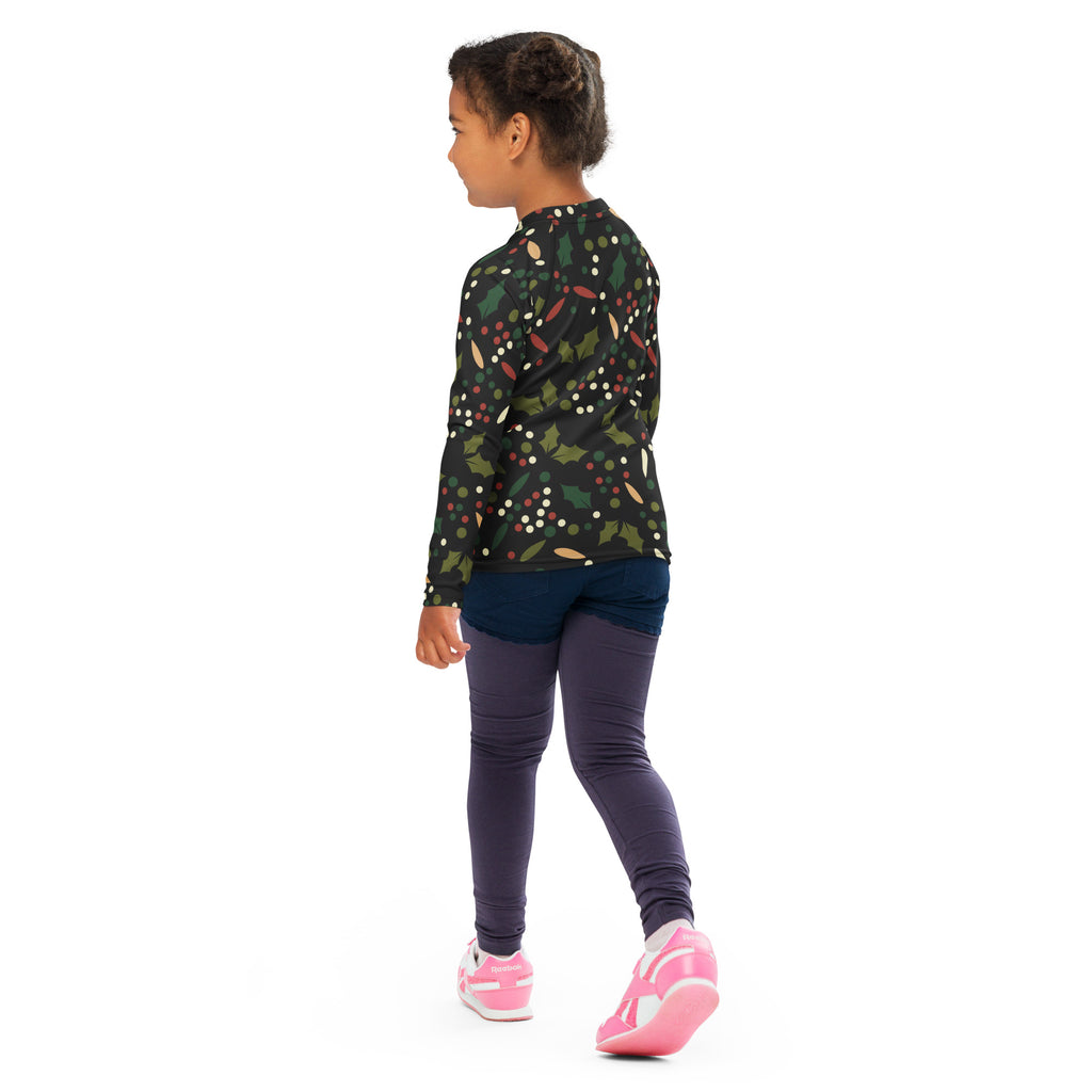 A child wearing a dark green kids holly christmas long sleeve rash guard swim shirt with upf 50 plus protective fabric