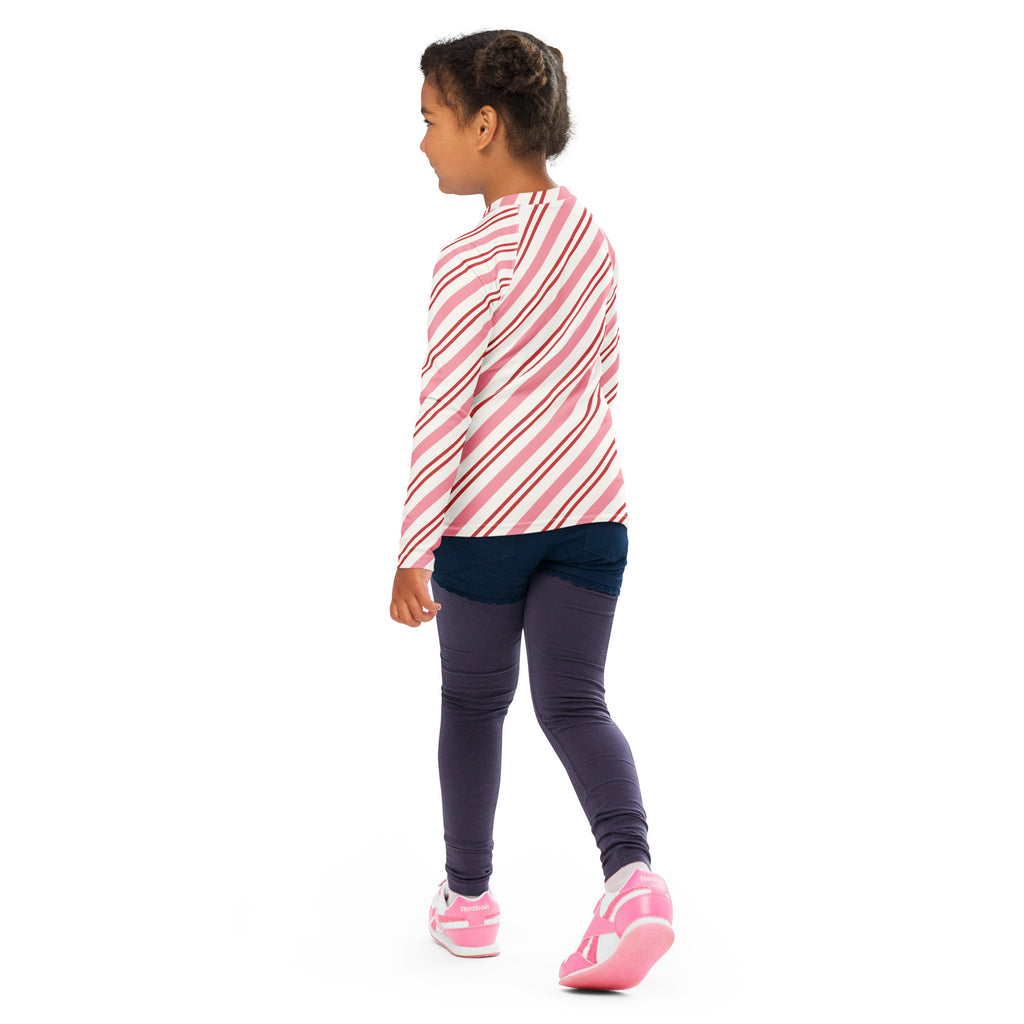 A child wearing a kids pink peppermint stripe christmas long sleeve rash guard swim shirt with upf 50 plus