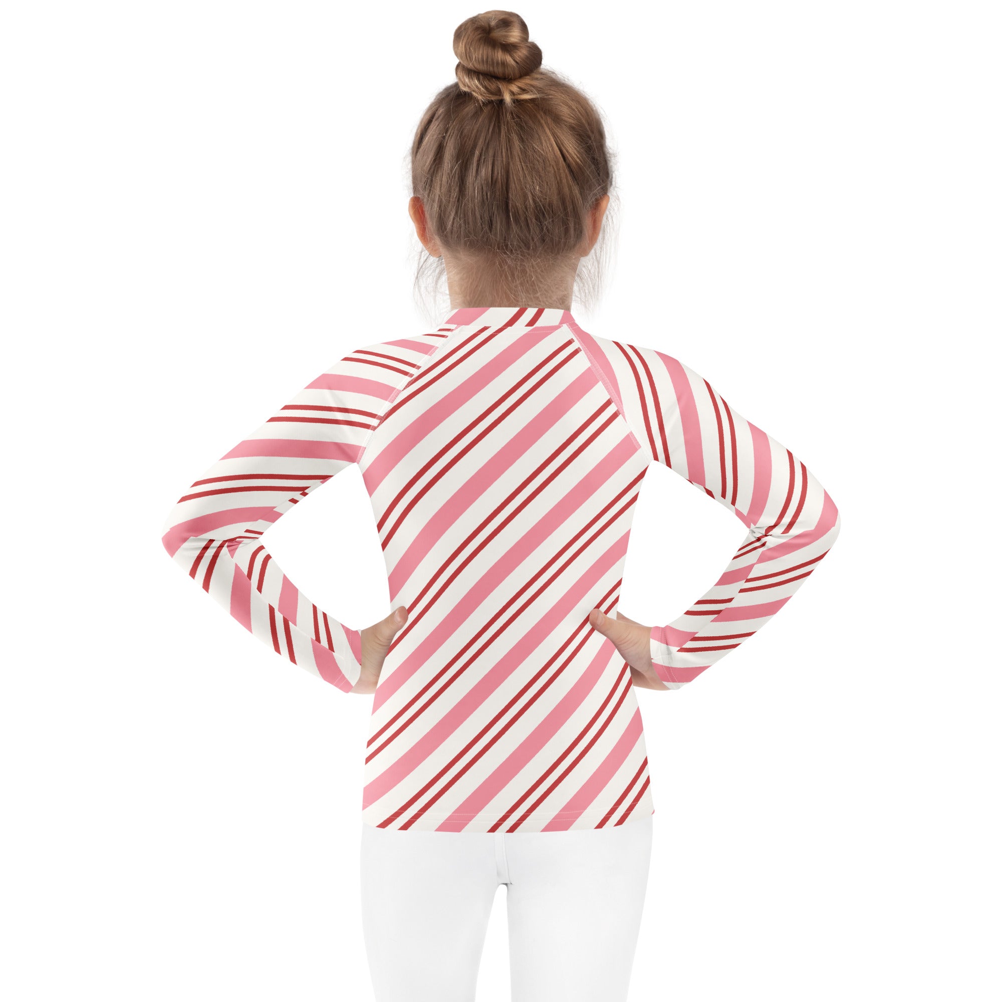 A girl wearing a kids pink peppermint stripe long sleeve rash guard swim shirt with upf 50+ and red accents