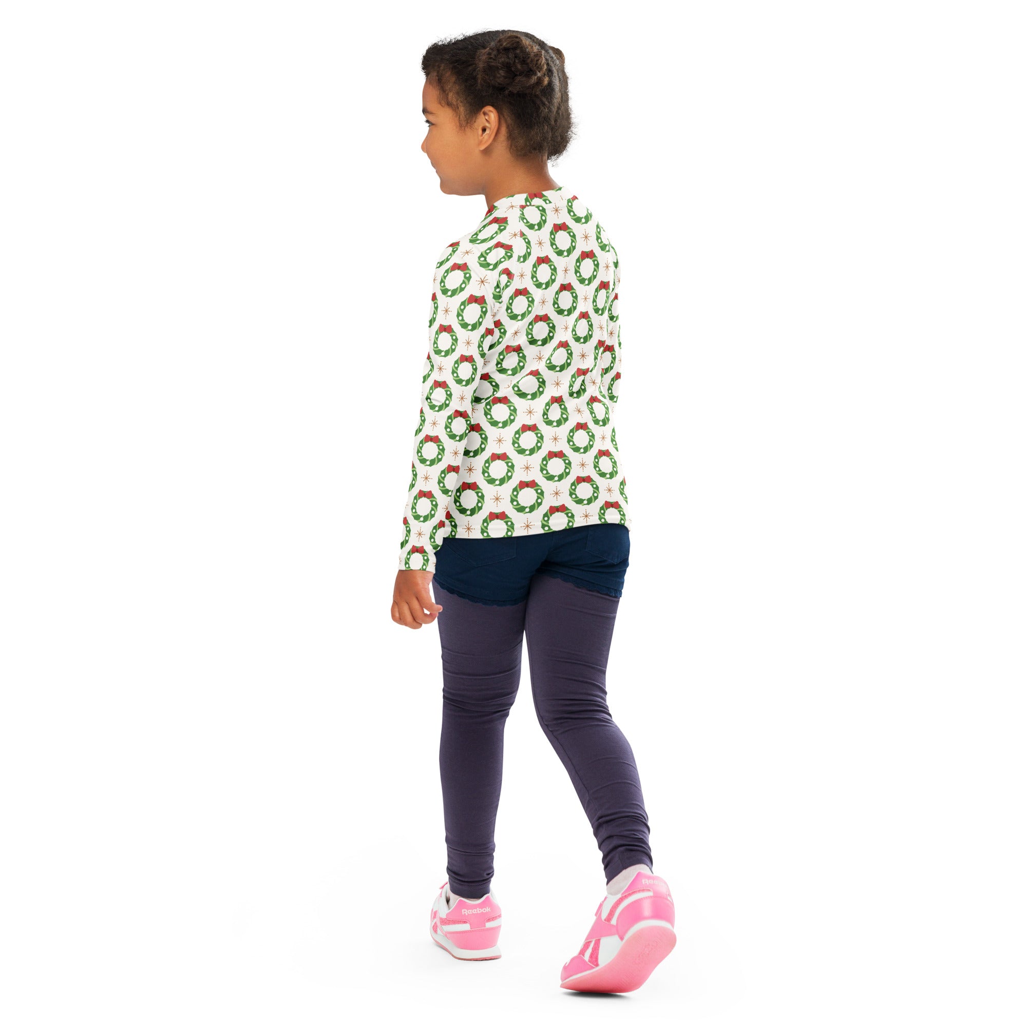 A child wearing a kids christmas wreath long sleeve rash guard swim shirt with upf 50 plus in white with green and red designs
