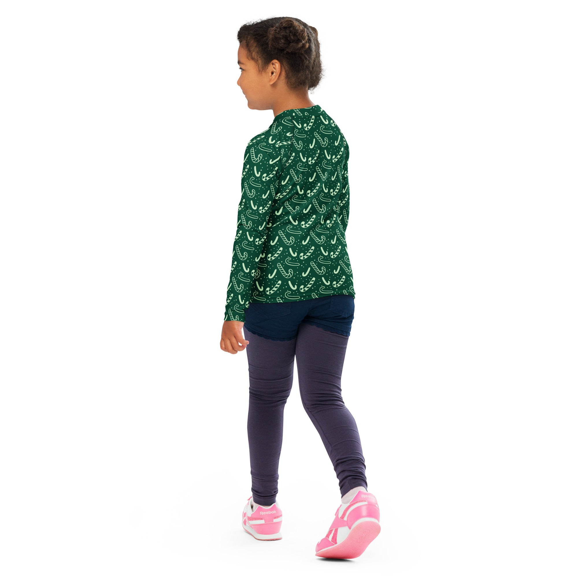 A child wearing a kids green candy cane Christmas long sleeve rash guard swim shirt with UPF 50 plus and leggings