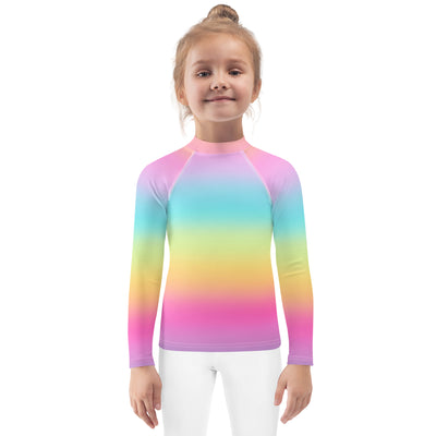 A child wearing a girls bright rainbow long sleeve rash guard swim shirt with UPF 50 plus in pink blue yellow and purple hues