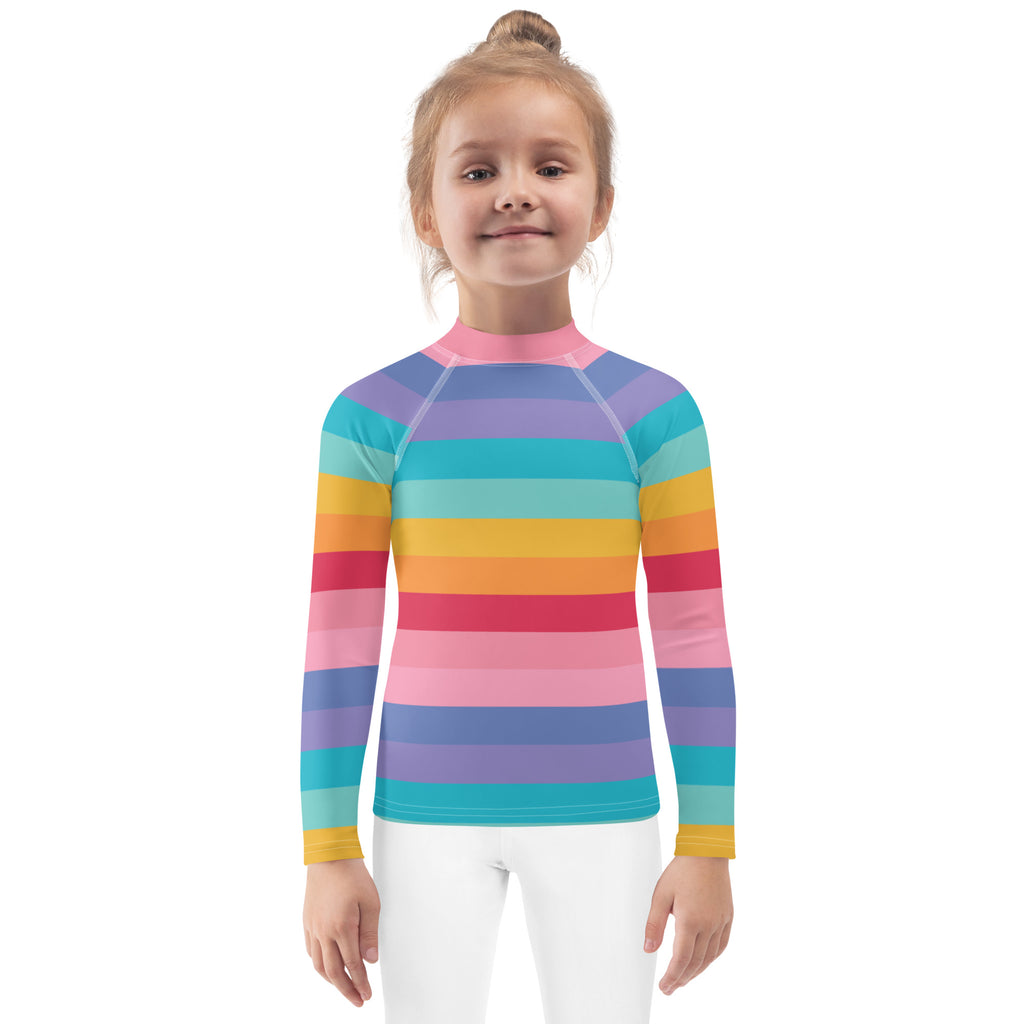 A girl wearing a bright rainbow long sleeve rash guard swim shirt with UPF 50 plus featuring vibrant stripes