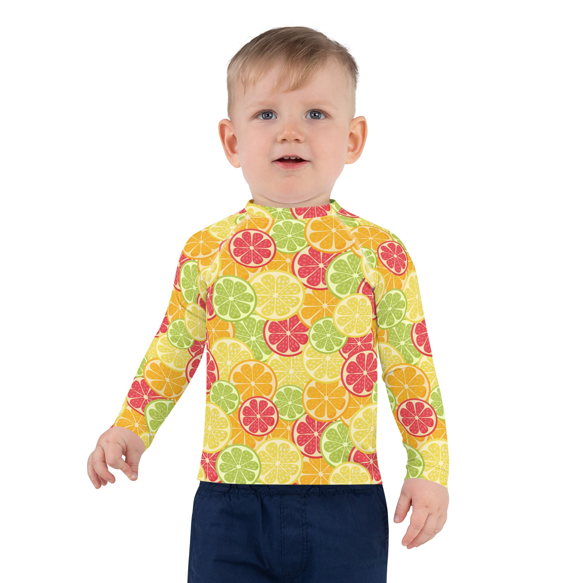 A vibrant kids citrus fruit long sleeve rash guard with playful sliced fruit pattern in yellow green and pink hues and UPF 50+