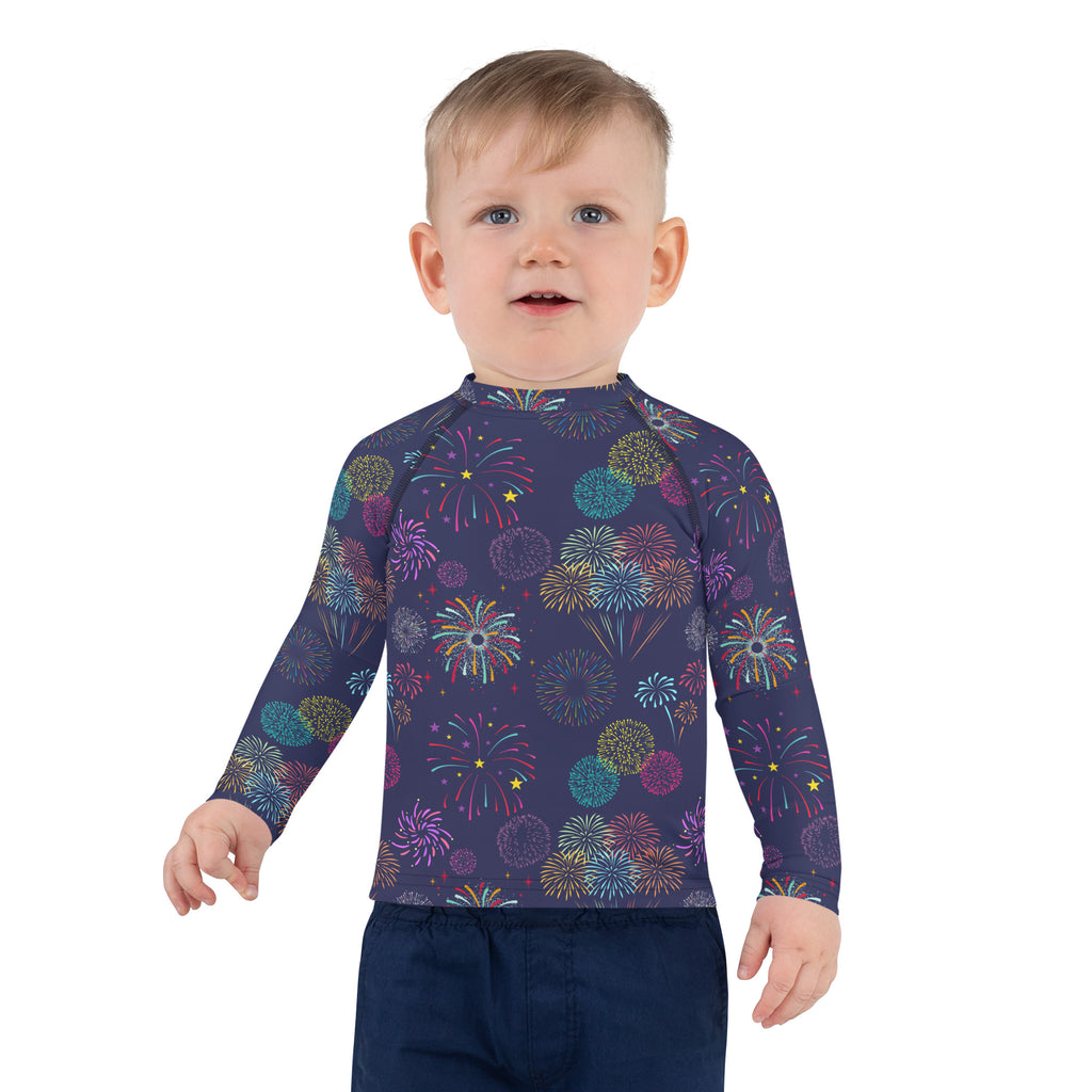 A child wearing a navy blue kids fireworks long sleeve rash guard swim shirt with vibrant patterns and UPF 50+ protection