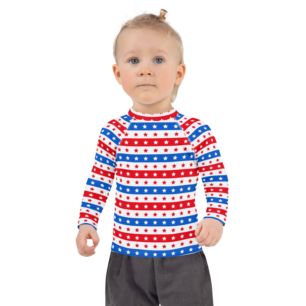 A child wearing a kids red white and blue stars and stripes long sleeve rash guard swim shirt with UPF 50+ protection