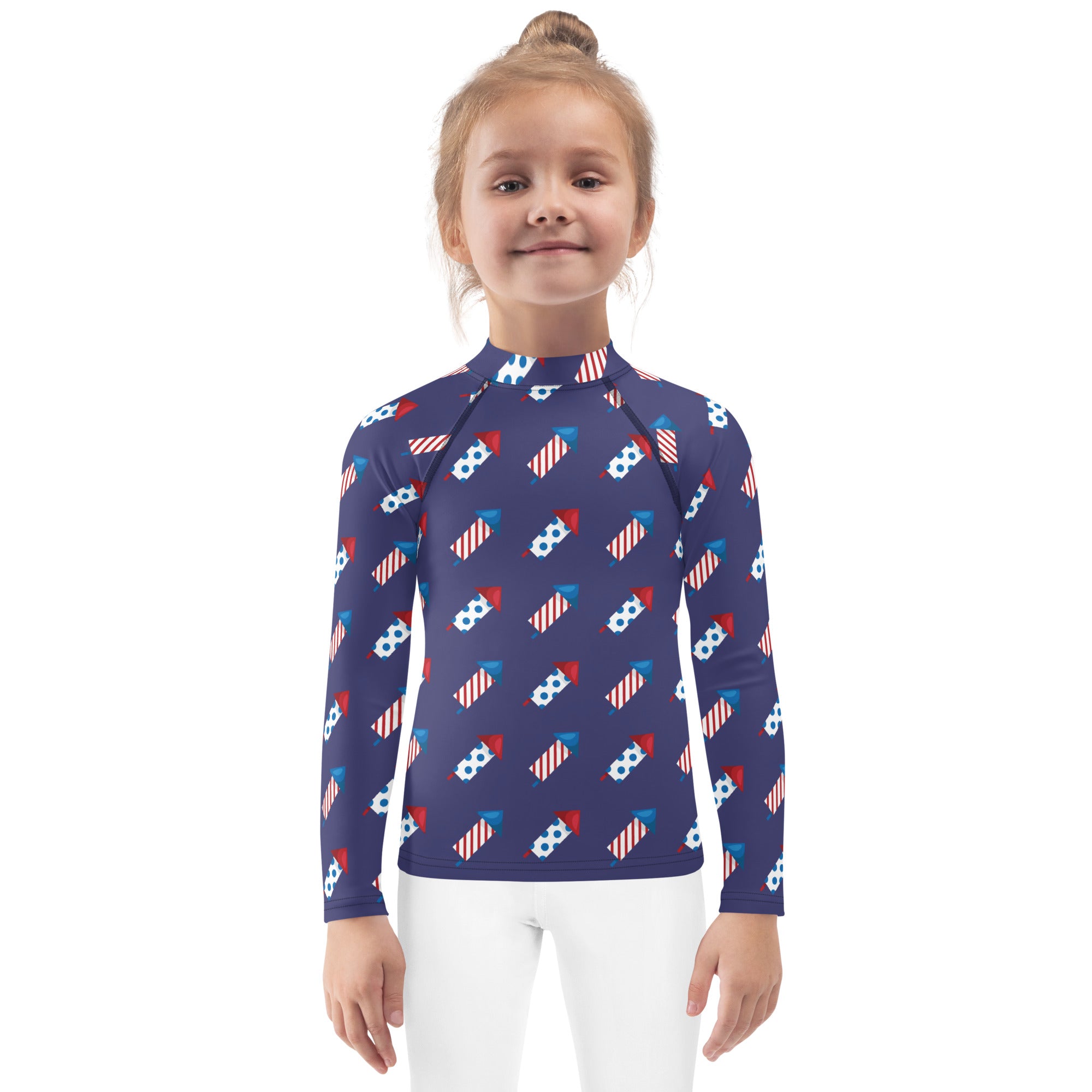 A navy blue kids firework rockets rash guard with long sleeves and a red white and blue fireworks pattern with UPF 50+