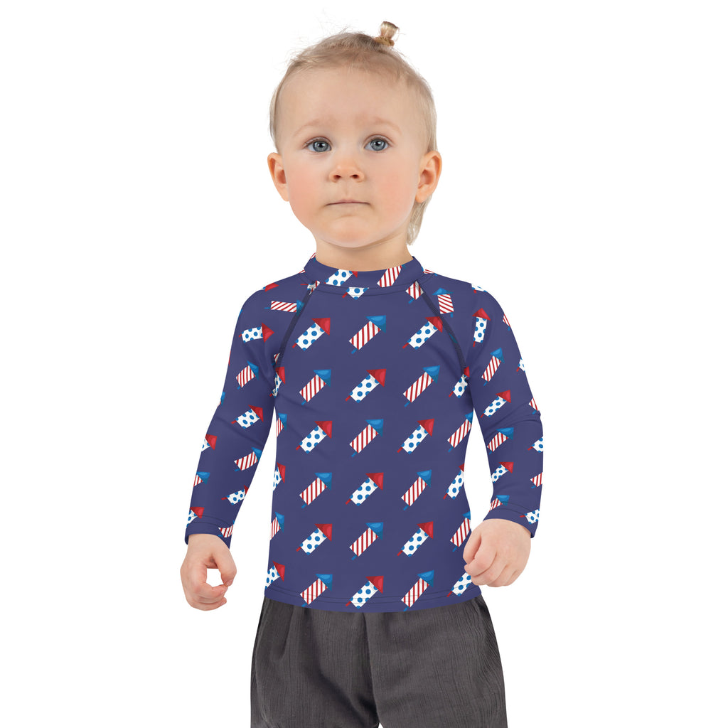 Navy blue kids long sleeve rash guard swim shirt with red white and blue fireworks pattern and upf 50 plus protection