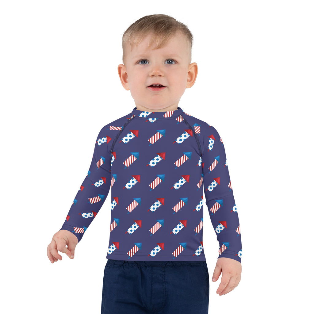 A navy blue kids long sleeve rash guard with red white and blue firework pattern and UPF 50 plus sun protection