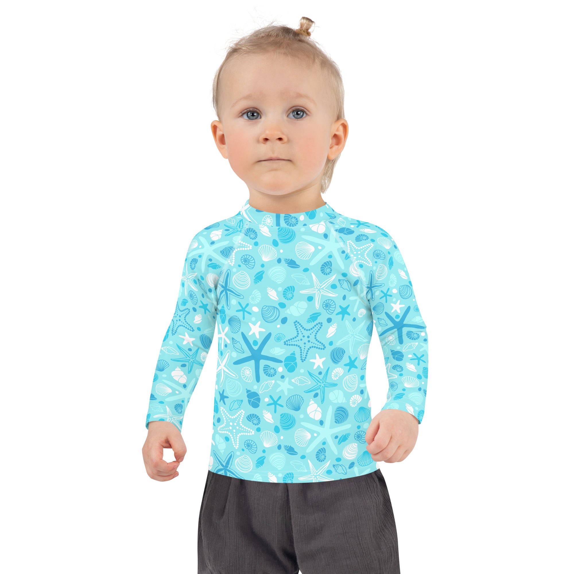 A child wearing a light blue kids starfish and seashell long sleeve rash guard with upf 50 plus for sun protection
