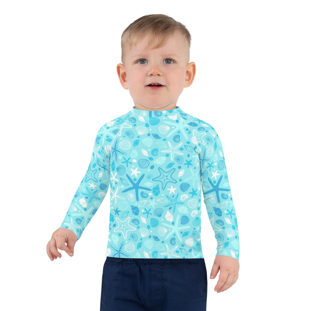 A light blue kids long sleeve rash guard swim shirt with starfish and seashell pattern and UPF 50+ protection