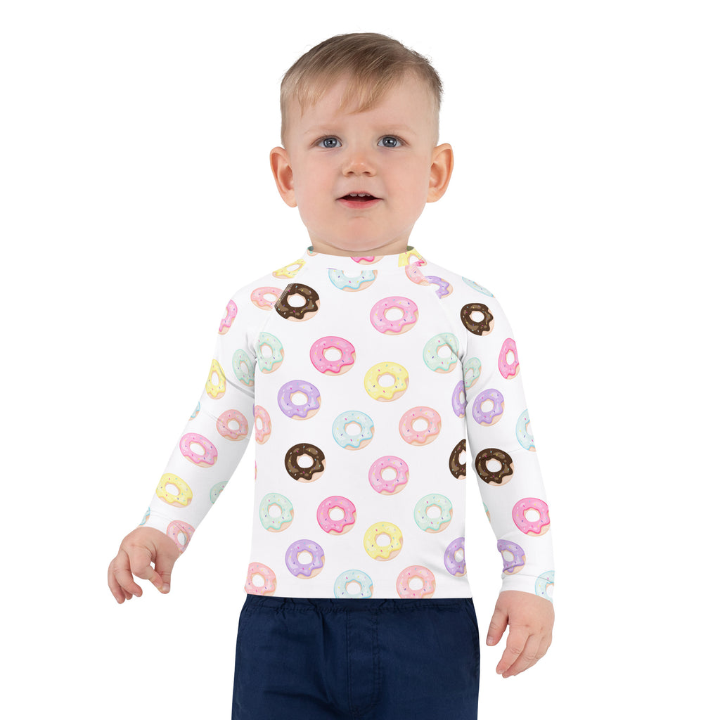 A child wearing a white kids colorful donuts long sleeve rash guard swim shirt with UPF 50 plus protection