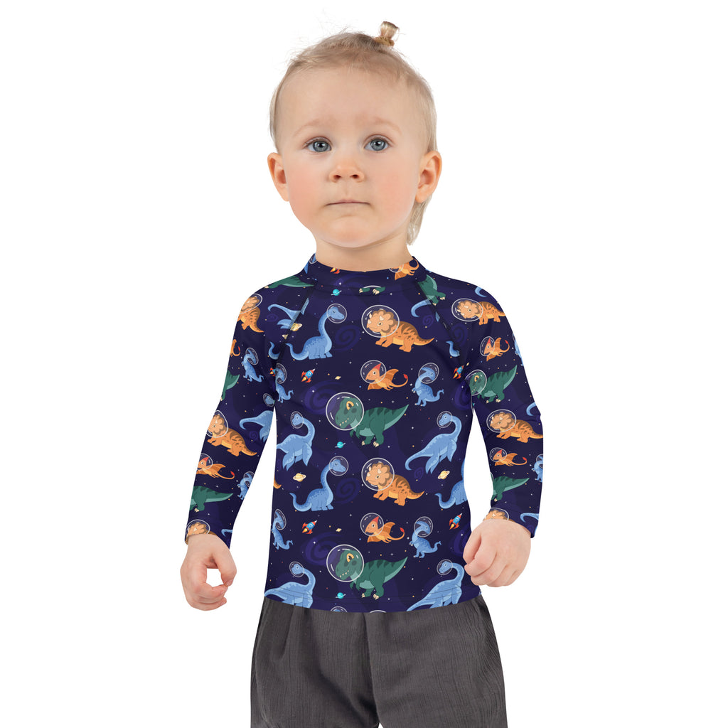 A navy blue kids long sleeve rash guard swim shirt with UPF 50+ featuring cartoon dinosaurs in space pattern