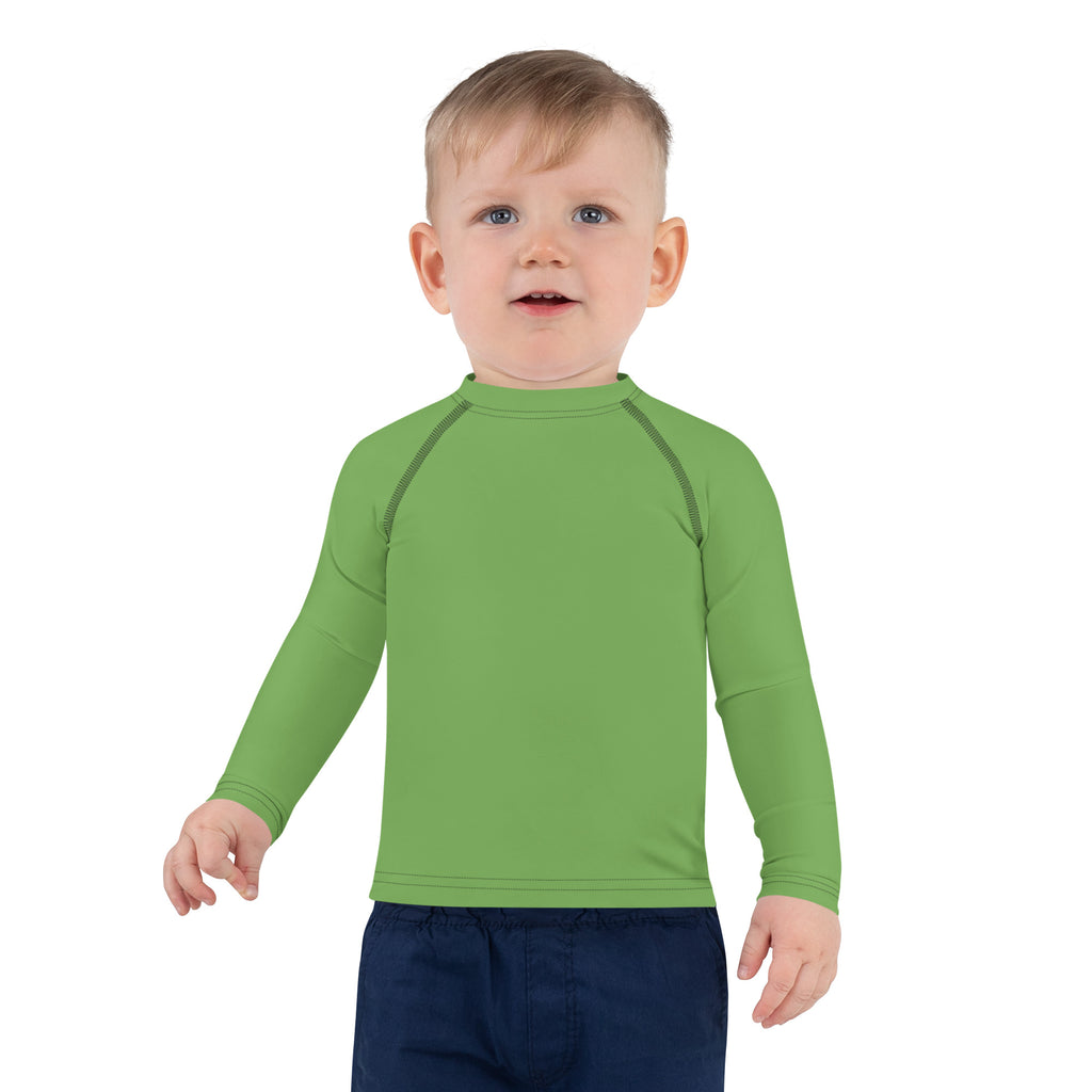 A child wearing a kids green long sleeve rash guard swim shirt with UPF 50 and dark stitching on raglan sleeves