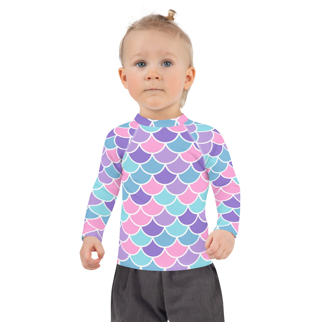 A child wearing a girls pastel mermaid scales long sleeve rash guard swim shirt with UPF 50 plus protection