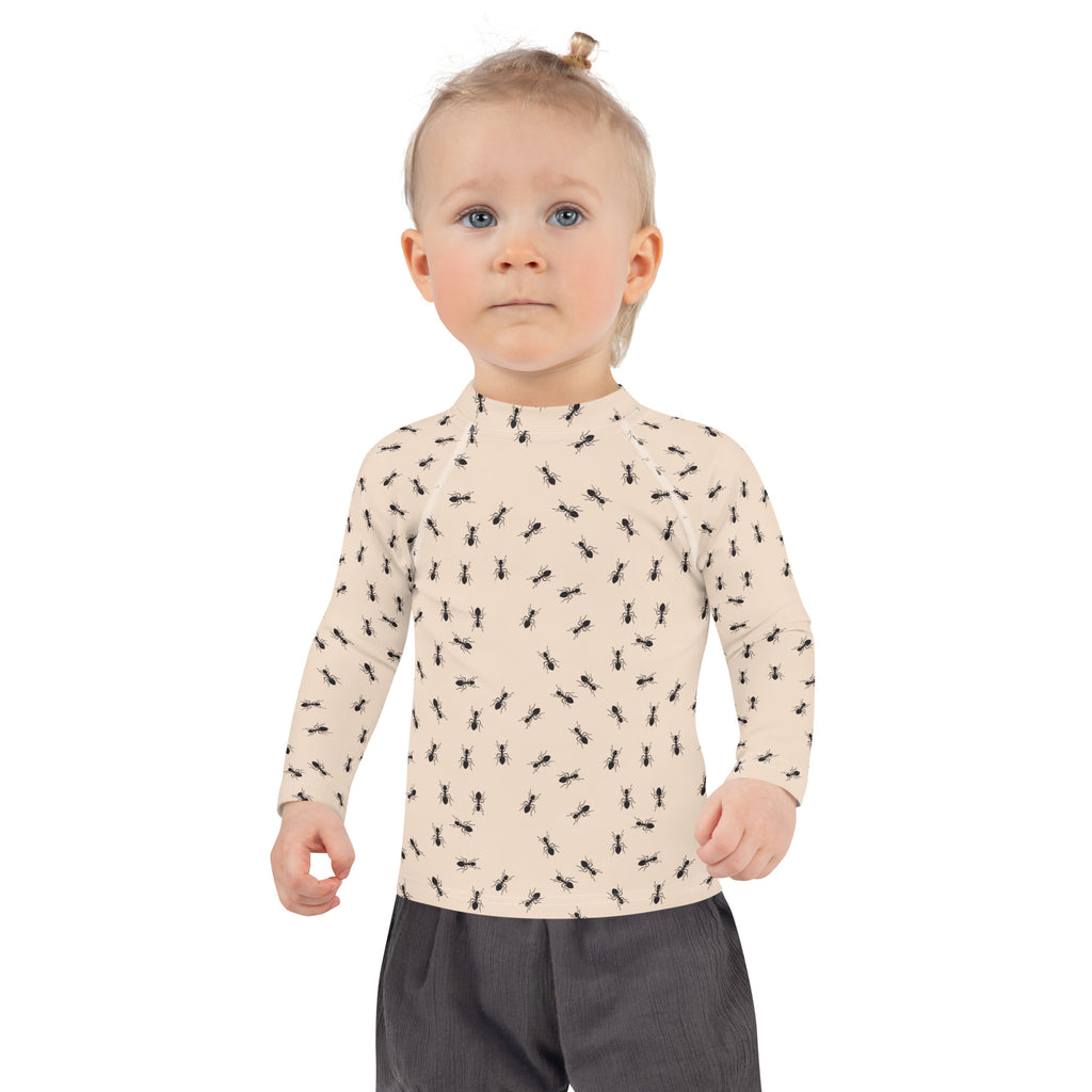 A child wearing a beige kids ant pattern long sleeve rash guard swim shirt with upf 50 plus for sun protection