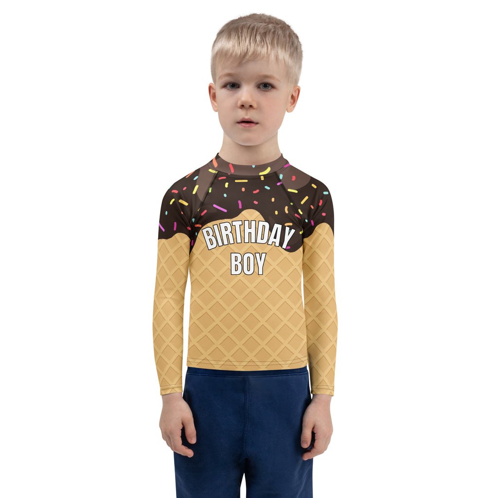 A child wearing a birthday boy chocolate ice cream cone long sleeve rash guard swim shirt with UPF 50 and sprinkles design