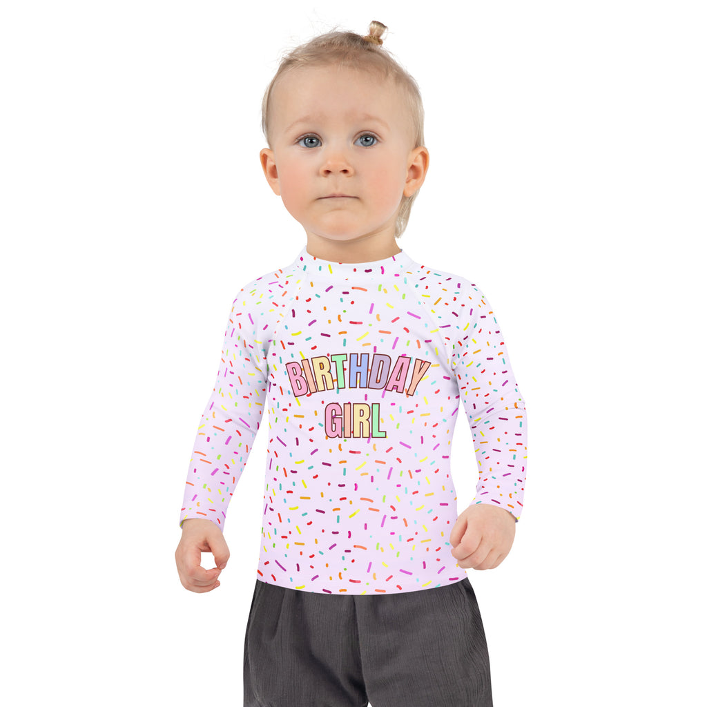 Pink long sleeve rash guard swim shirt with birthday girl graphic colorful sprinkles pattern and UPF 50 plus protection