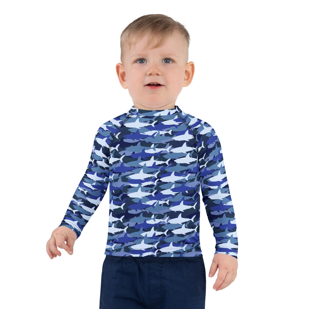A child wearing a kids blue shark long sleeve rash guard swim shirt with upf 50 and shark camouflage pattern