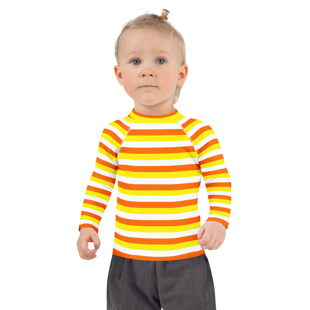A child wearing a kids candy corn stripes halloween long sleeve rash guard swim shirt in yellow orange and white