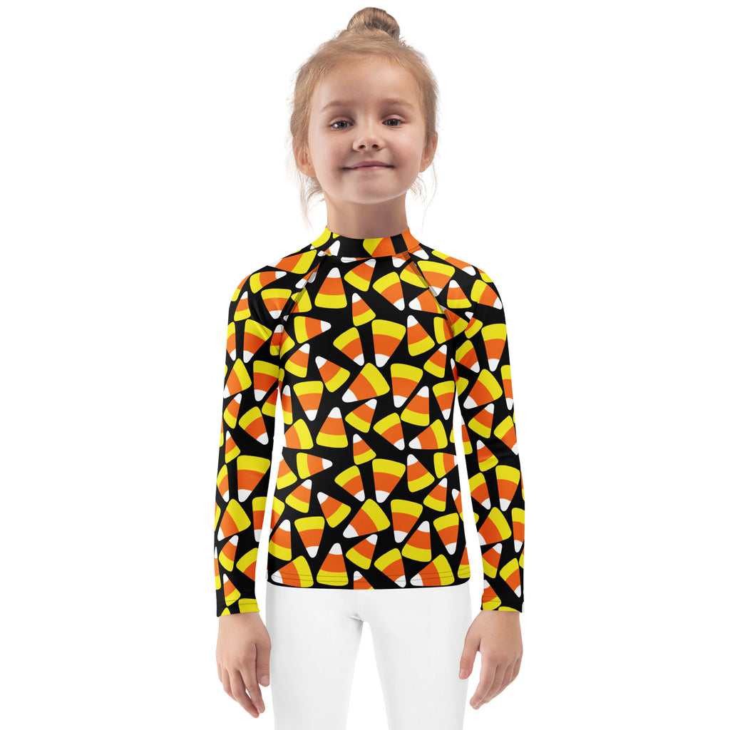 A kids candy corn halloween long sleeve rash guard swim shirt in black with orange yellow and white candy corn and upf 50+ protection