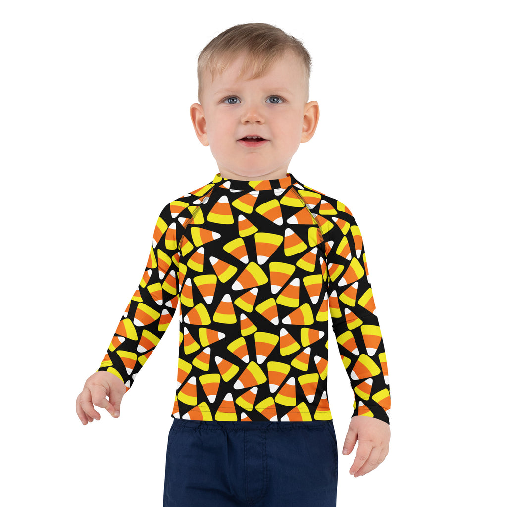 A child wearing a black long sleeve kids candy corn Halloween rash guard swim shirt with vibrant candy corn pattern and UPF 50+