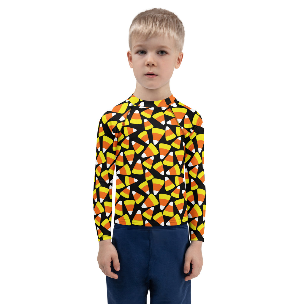 A child wearing a kids candy corn halloween long sleeve rash guard swim shirt with upf 50+ and candy corn pattern