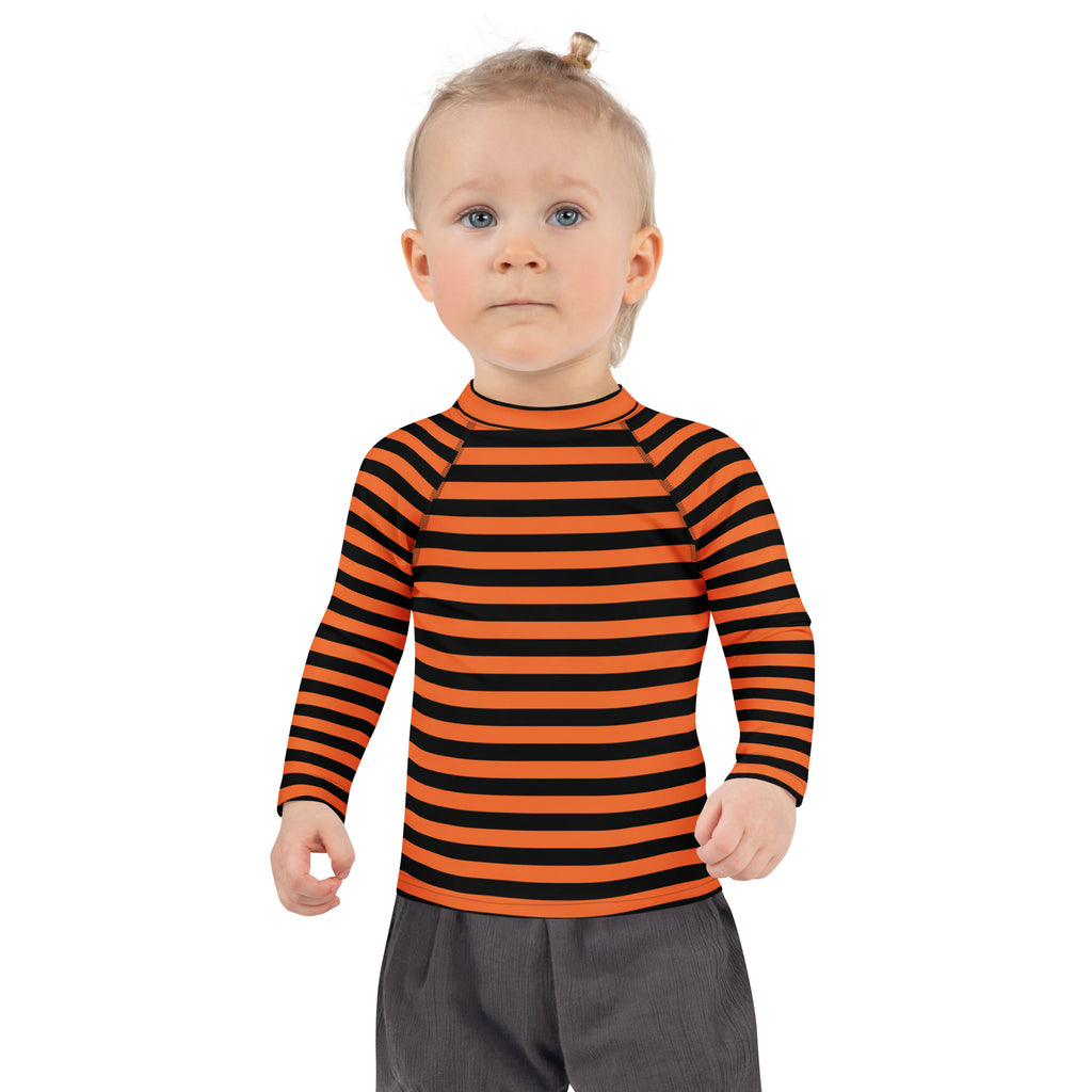 A child wearing a kids orange and black halloween long sleeve rash guard swim shirt with upf 50 and bold stripes