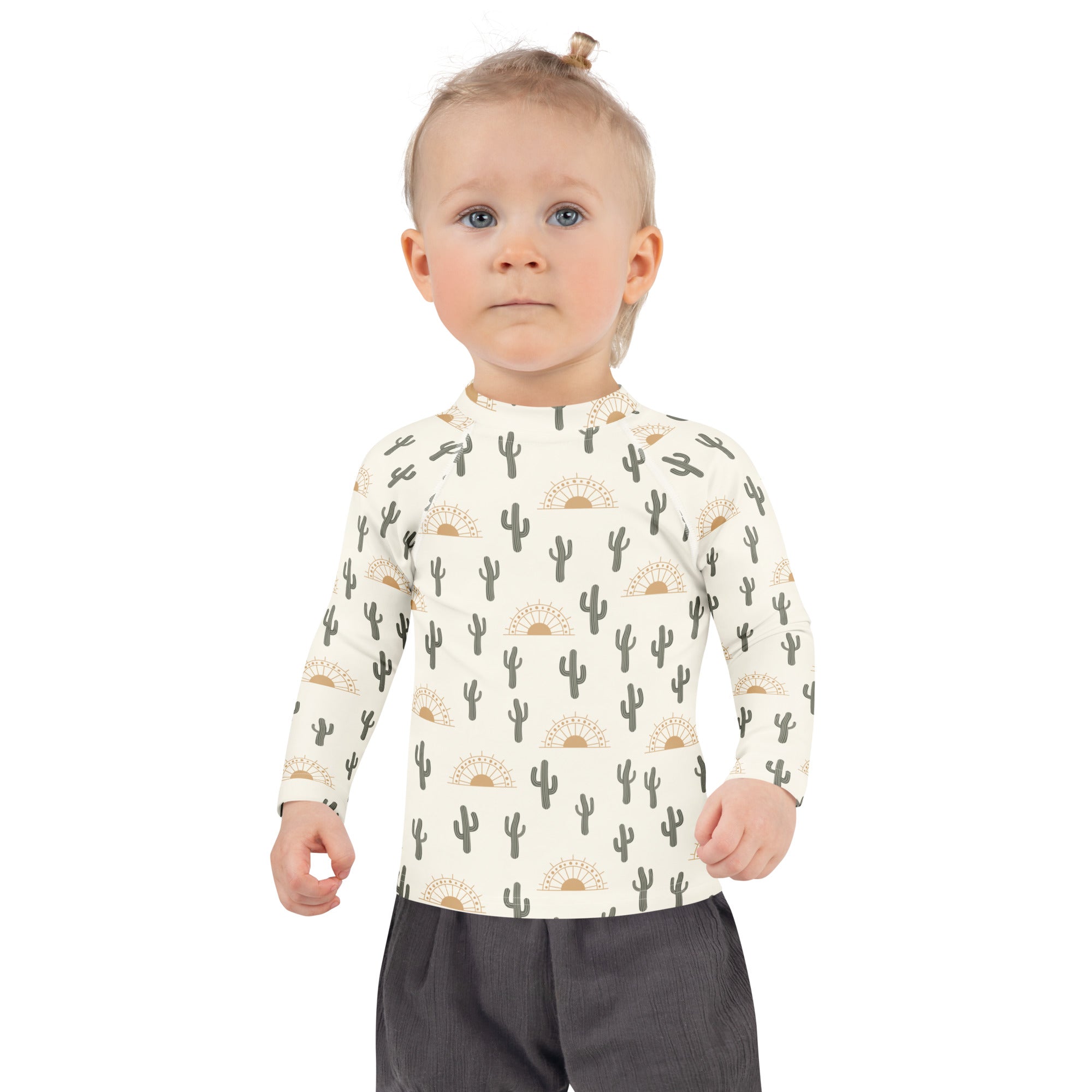 A child wearing a cream kids cactus desert sunrise long sleeve rash guard swim shirt with upf 50+ and black cactus print